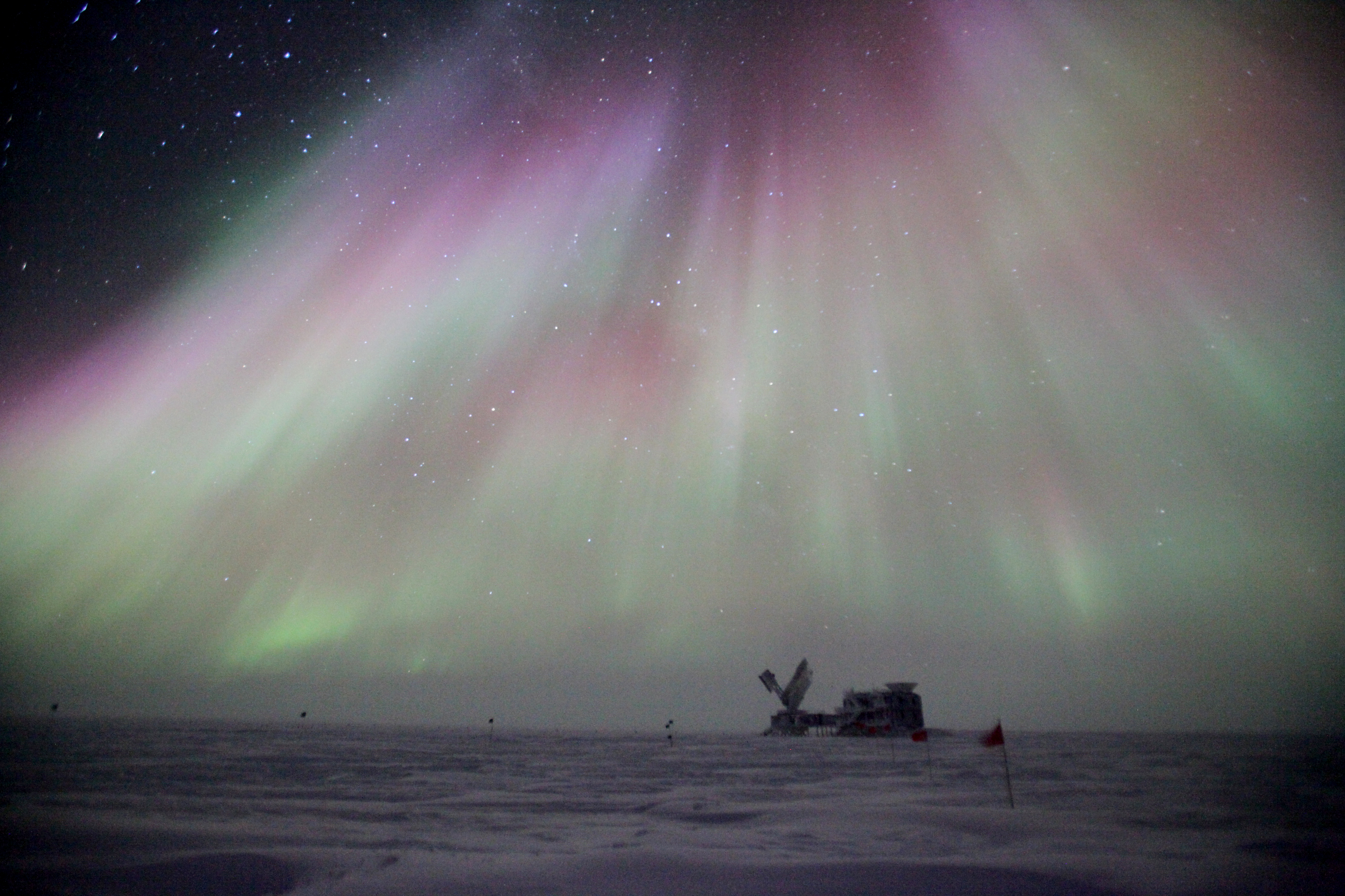 A night photo of auroras over a building.