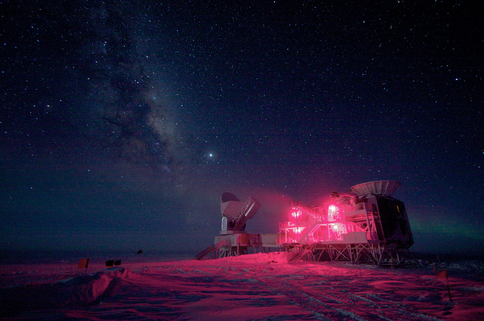 Science building at the South Pole lit with red lights against starry night sky.