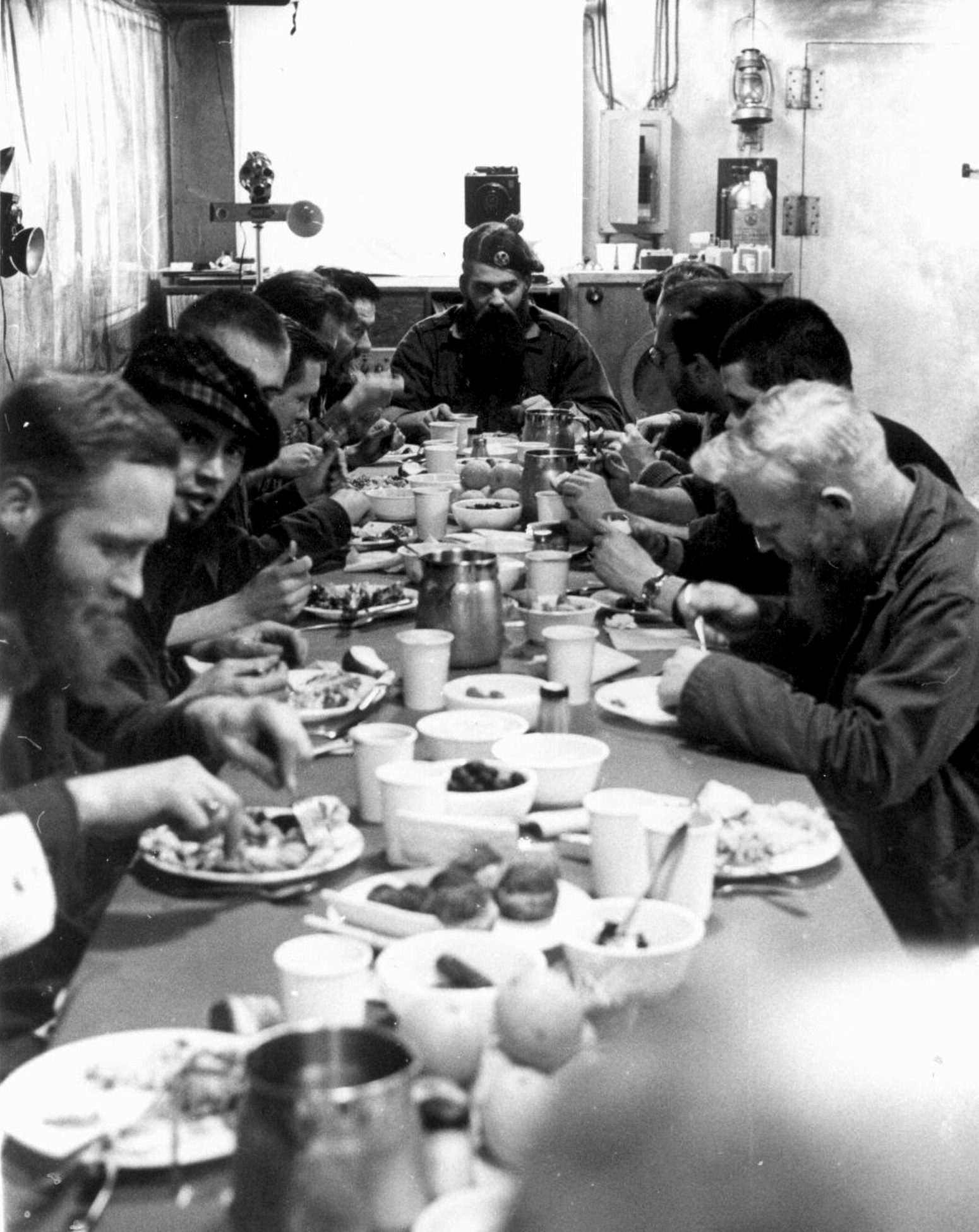 Men eat a meal at a long table.