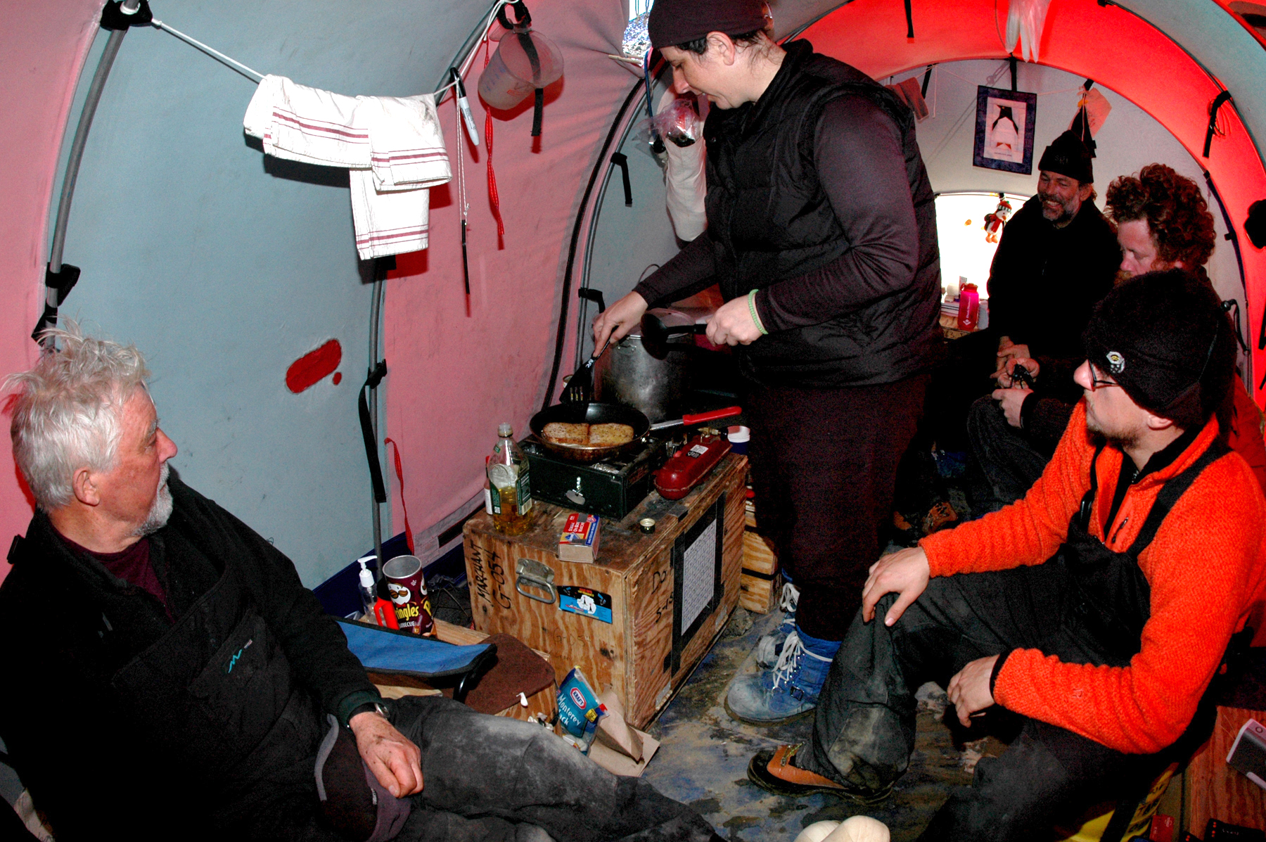 Several people in tent; one cooking.