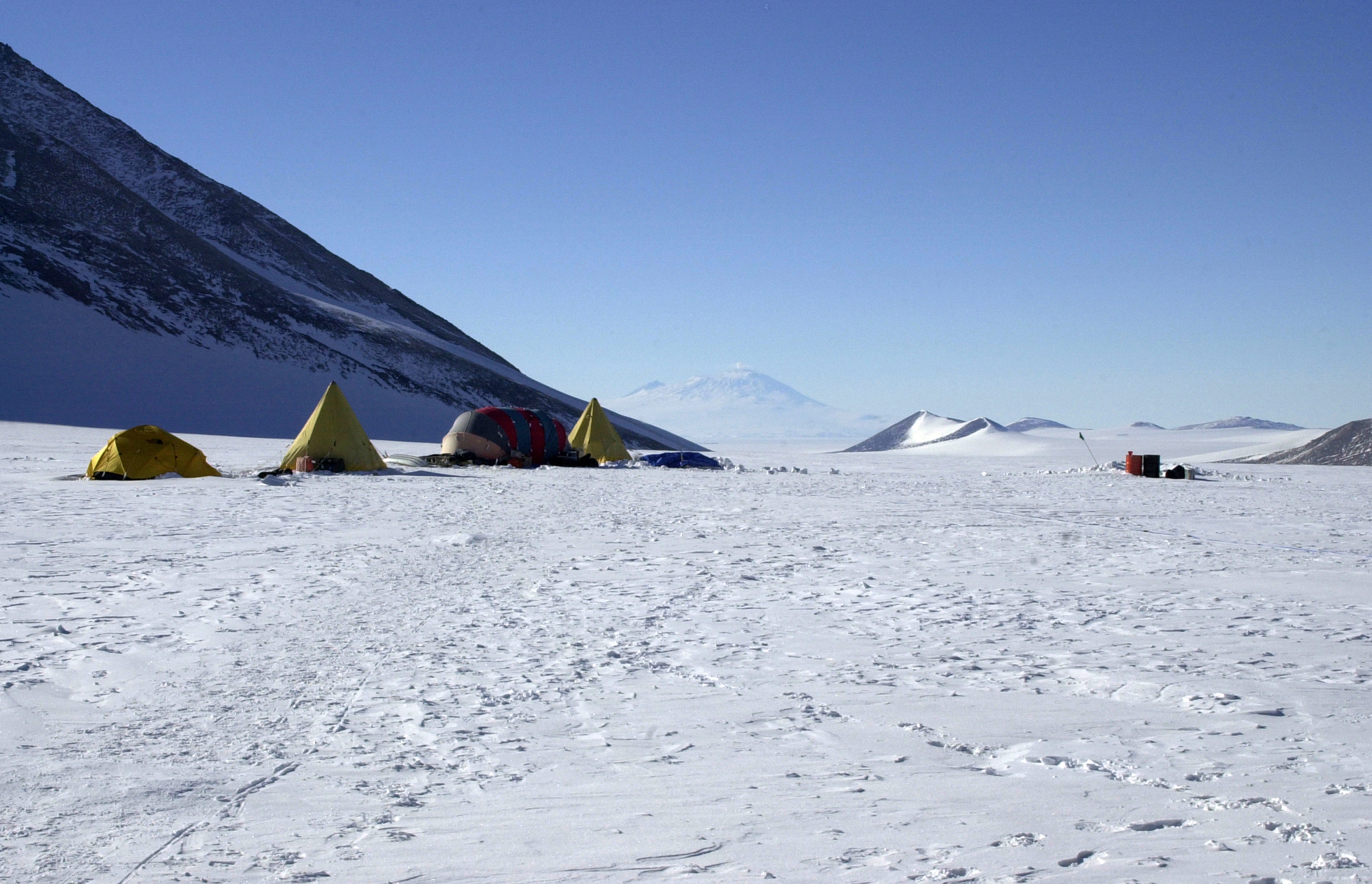 A small group of tents sits in the snow.