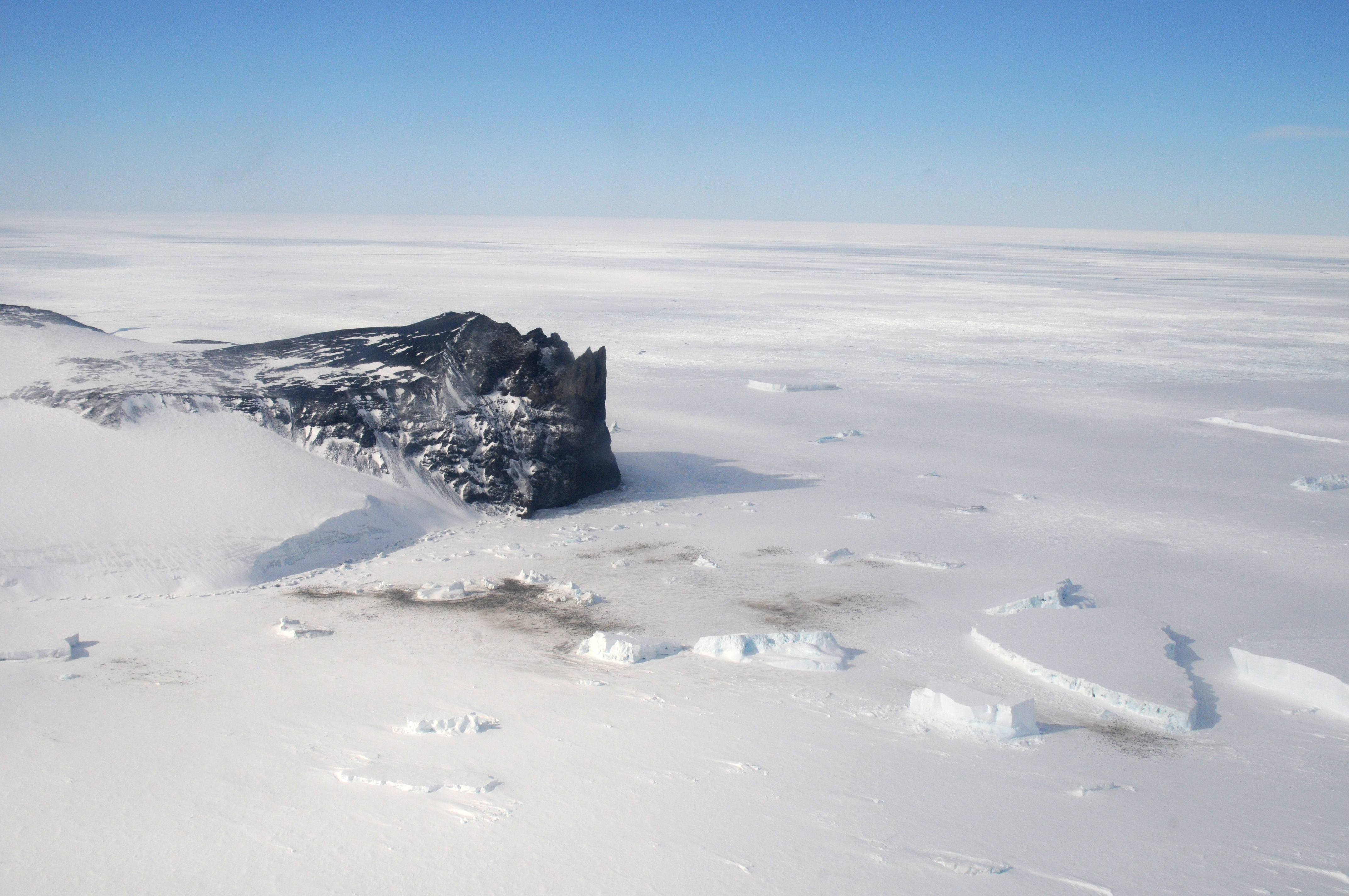 Aerial photo of snow, ice and rocky coastline.