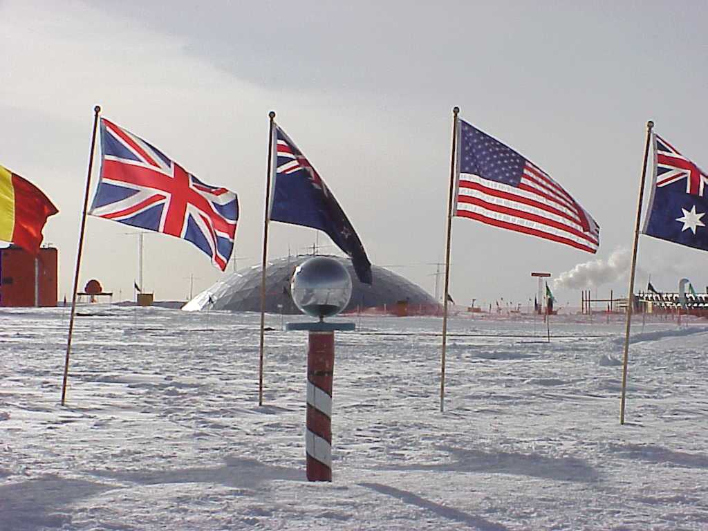 Flags surround a pole with globe on top, with a dome in the distance.