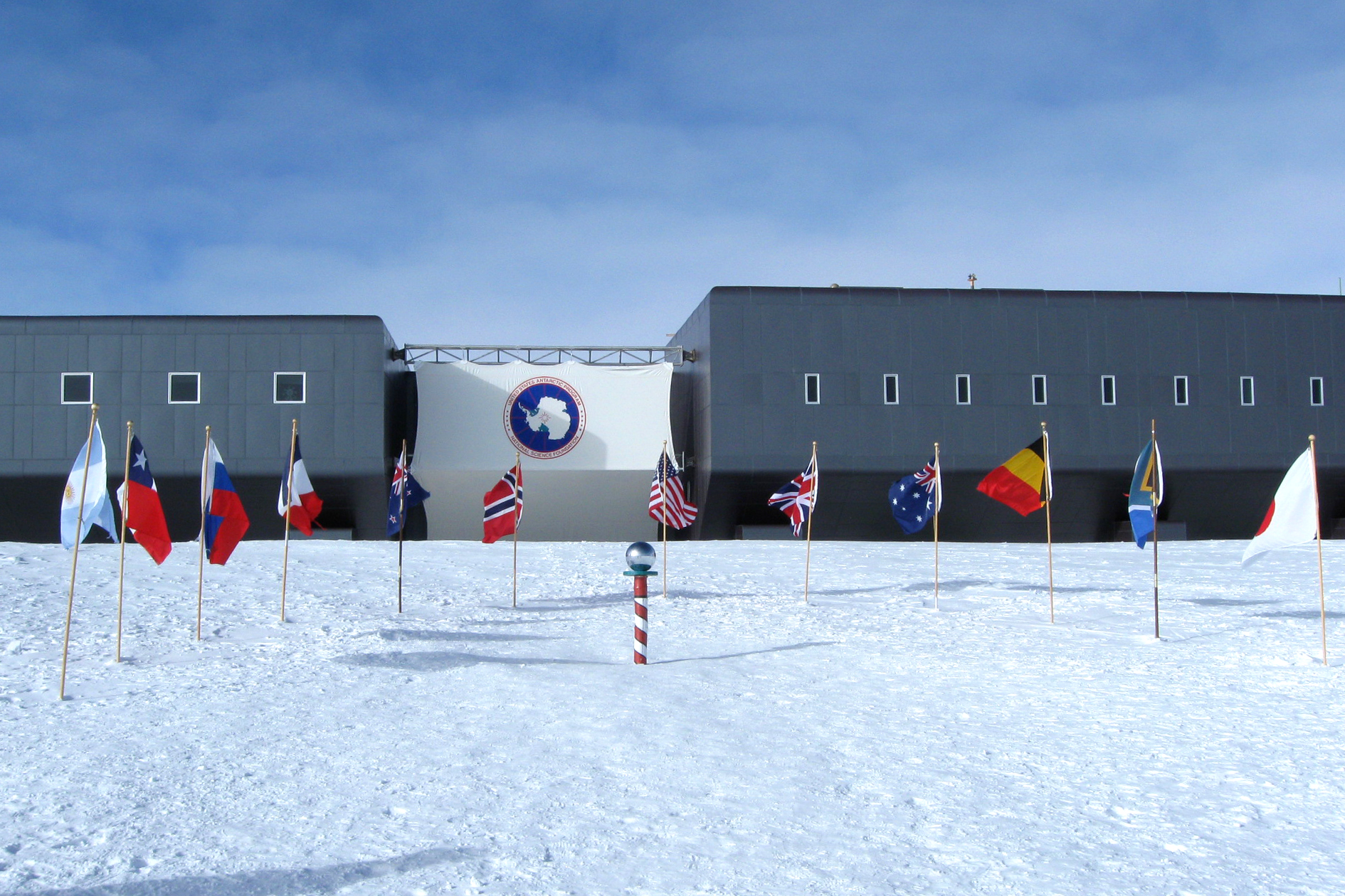 A building on snow with flags out front.