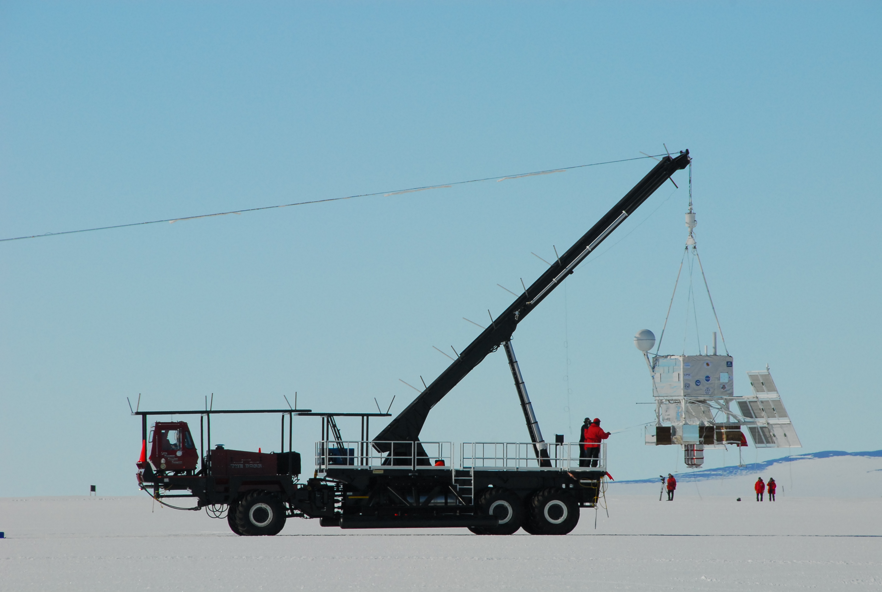 A large objects dangles off the end of a truck.