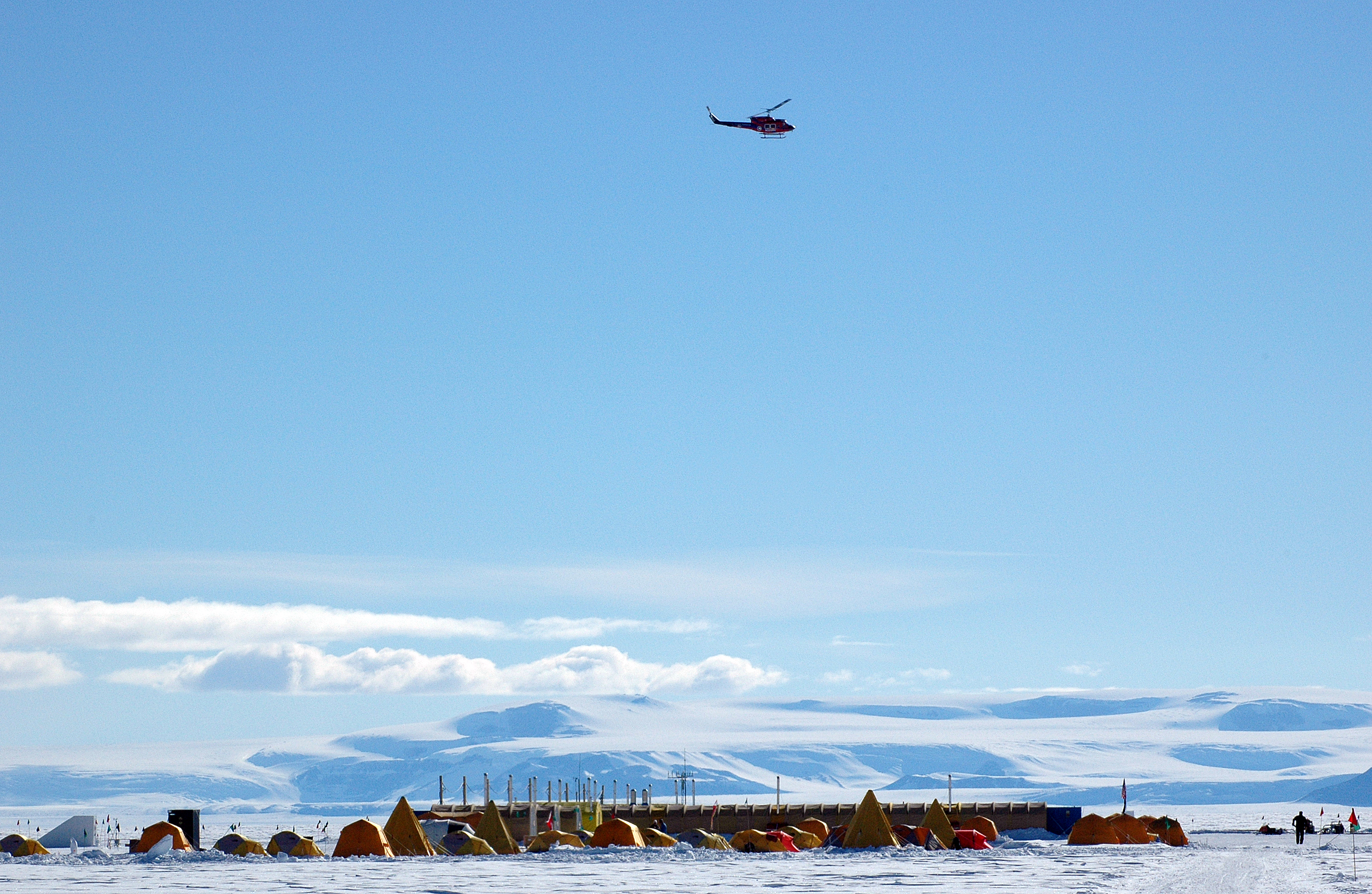 A helicopter flies over a field camp.