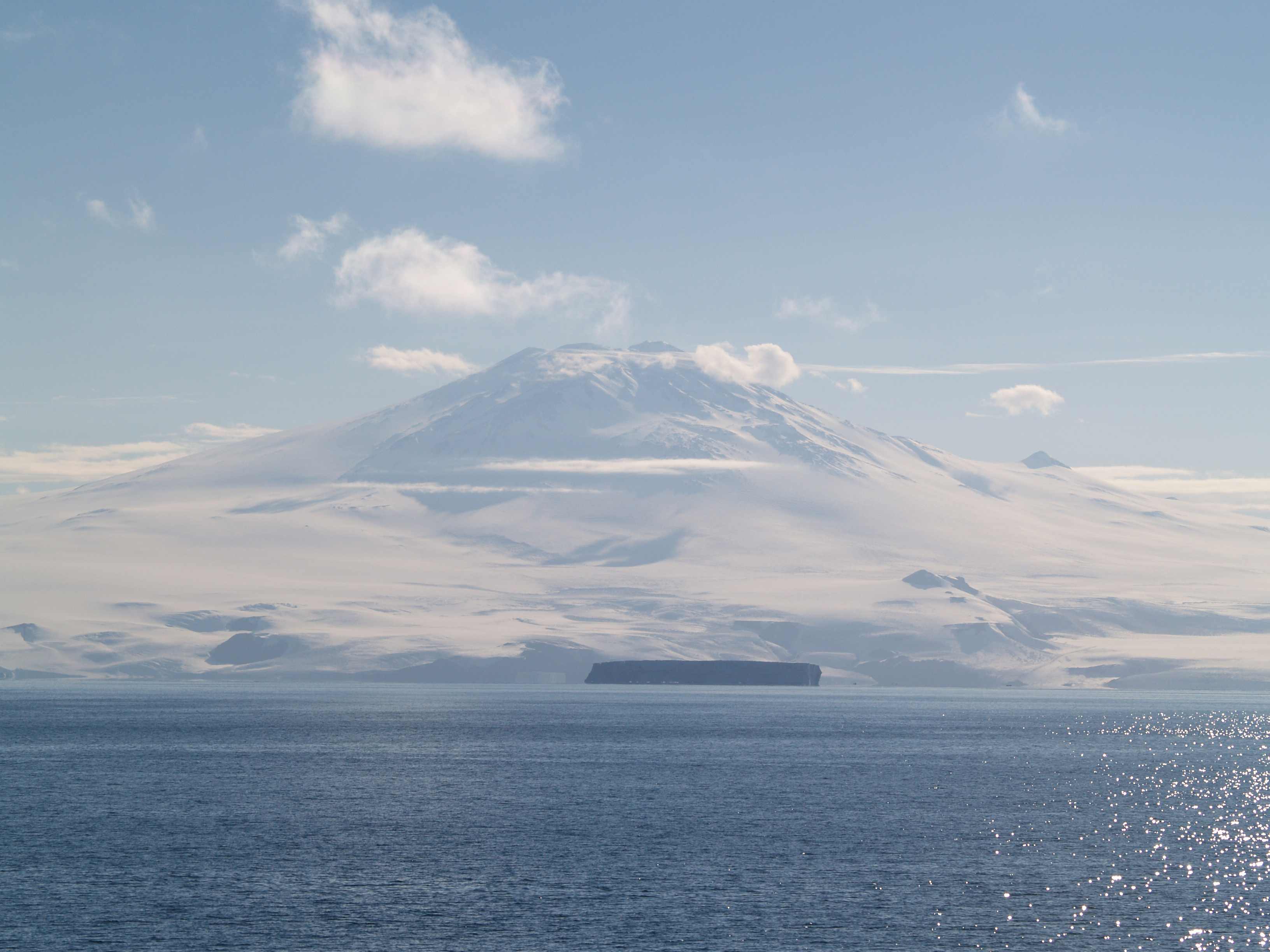 Snow covered mountain and ocean.