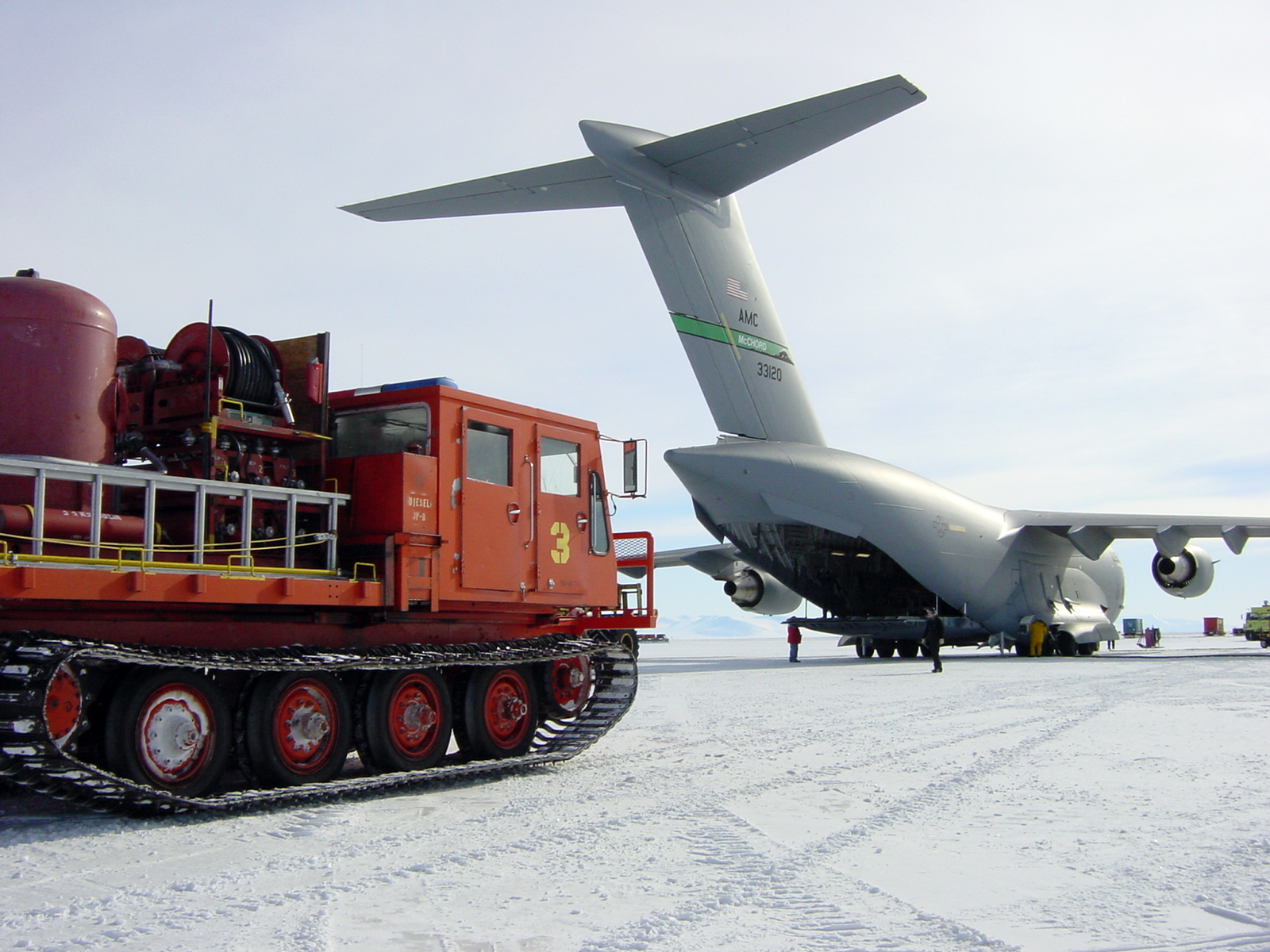 A truck parks near an airplane on ice.