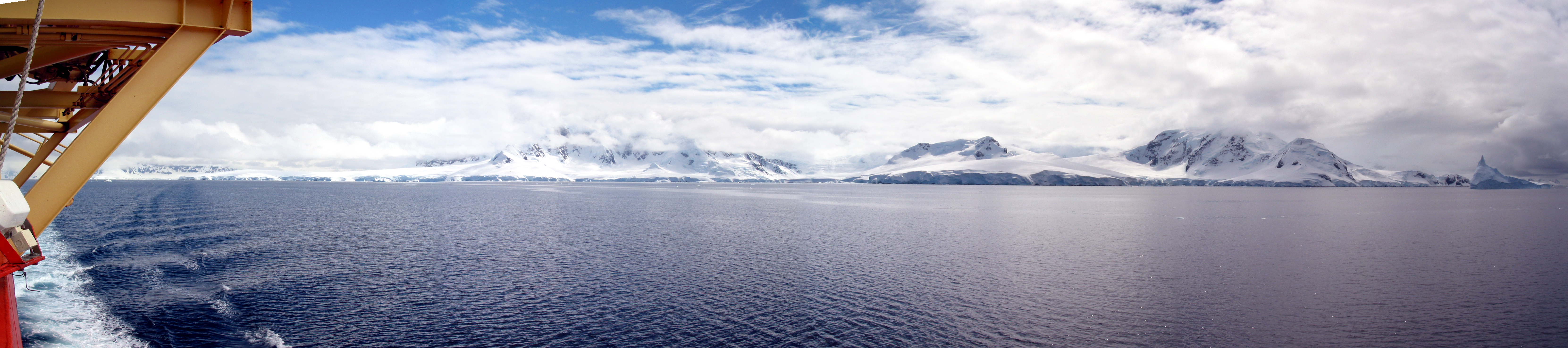 A view of water and snow-covered land from a ship.