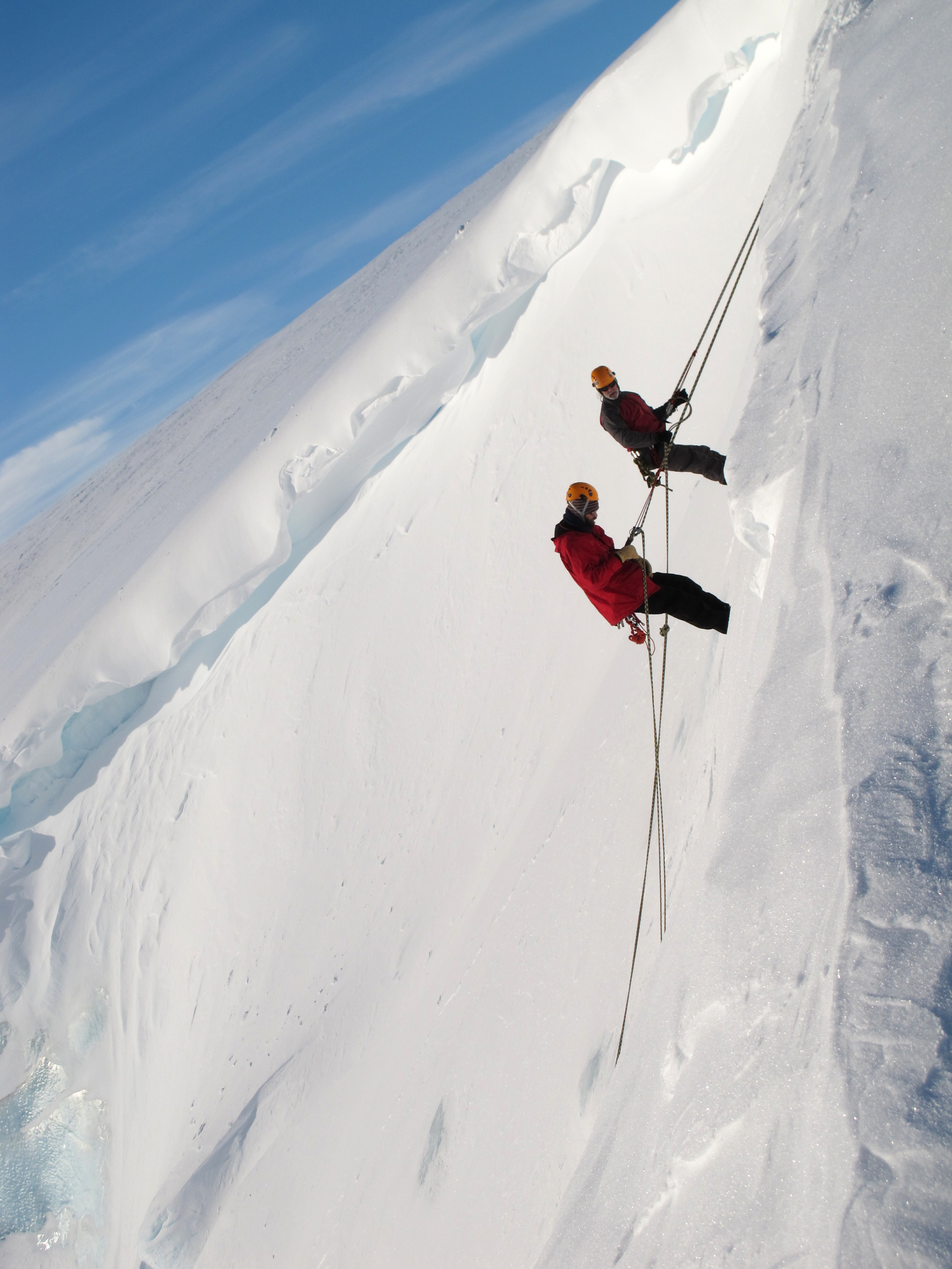 Two men climbing a glacier.