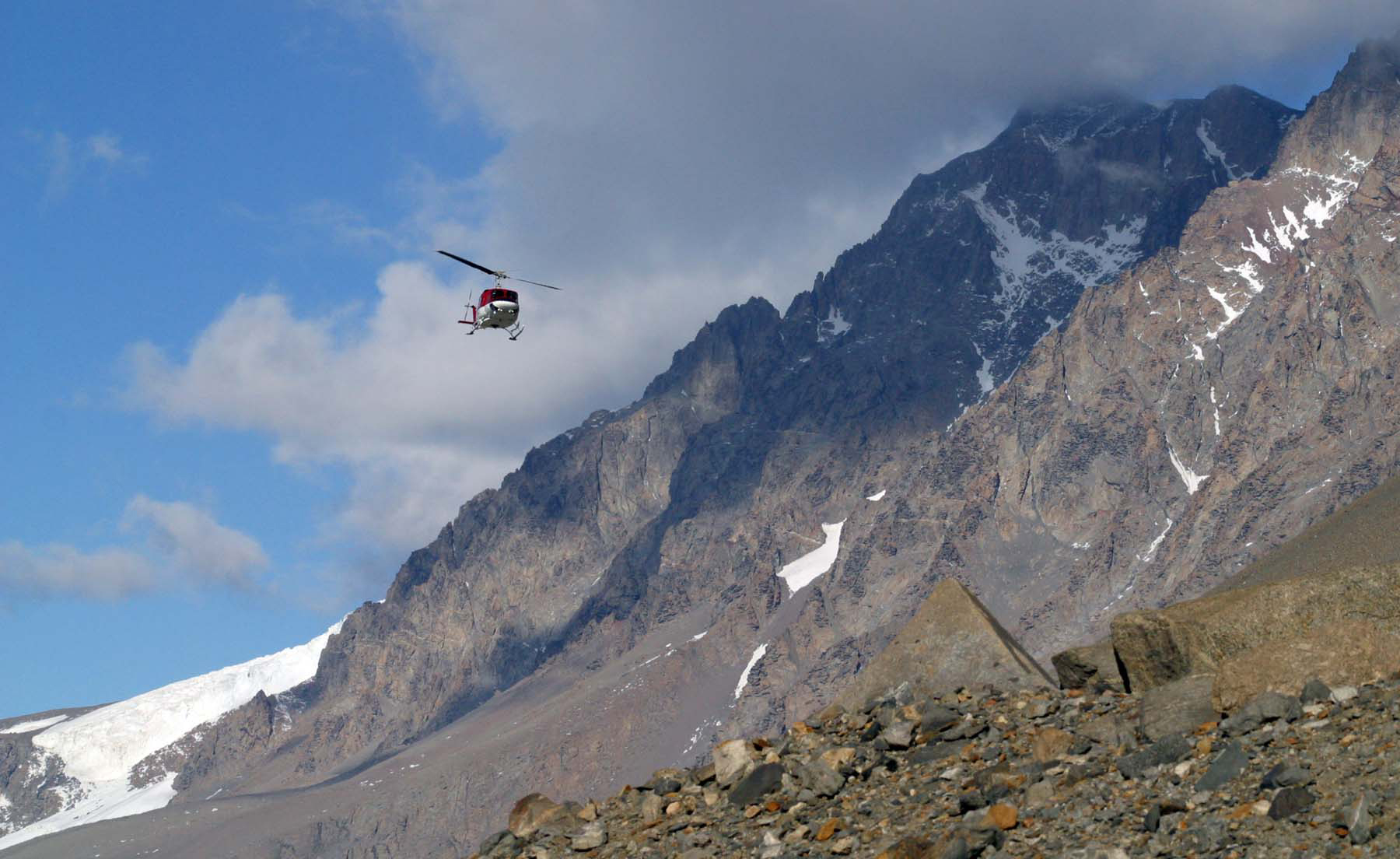 A helicopter flies near mountains.