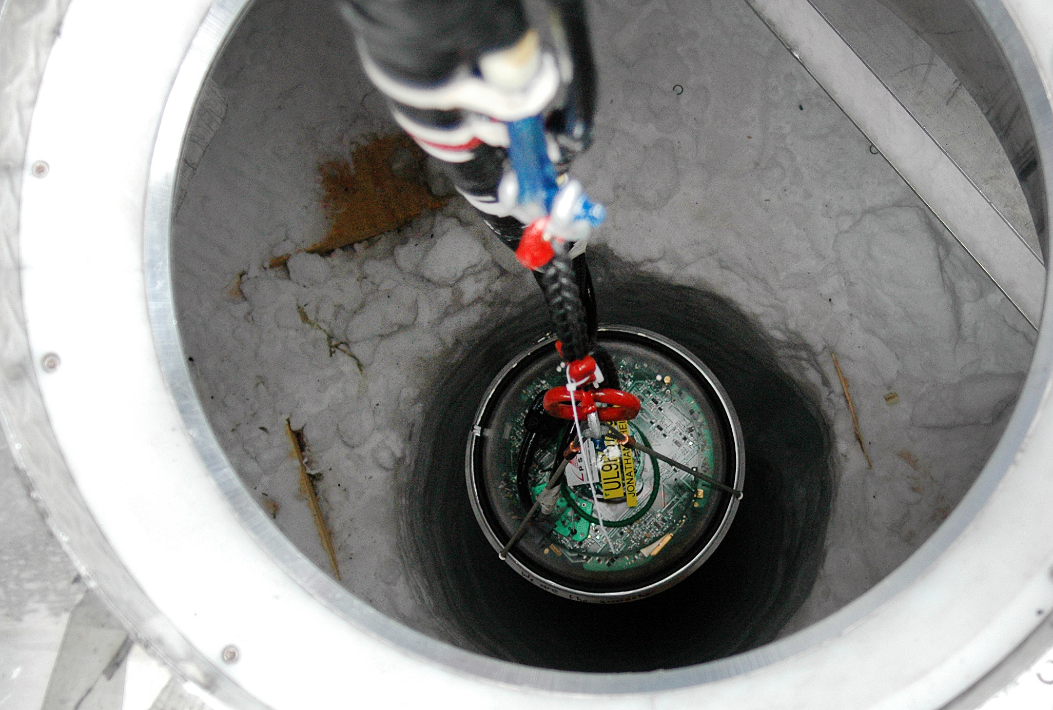 A sphere-shaped scientific instrument being lowered into a hole.