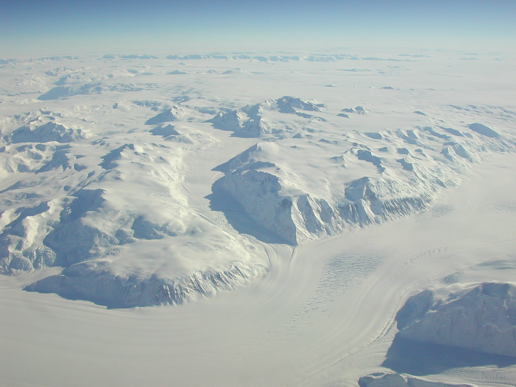 Aerial view of snow covered mountains and glacier streams.