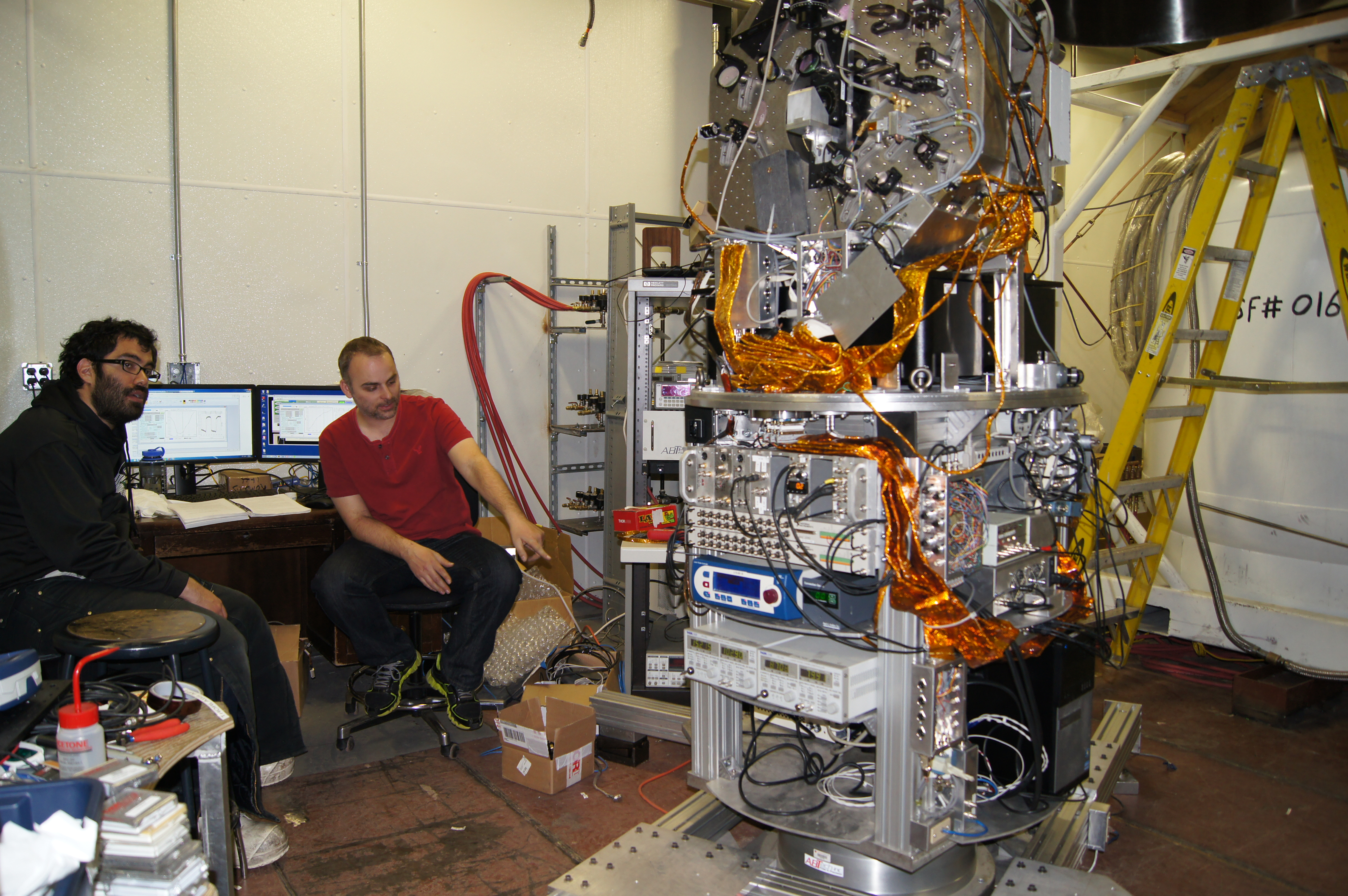 Two men by a large complex scientific instrument.