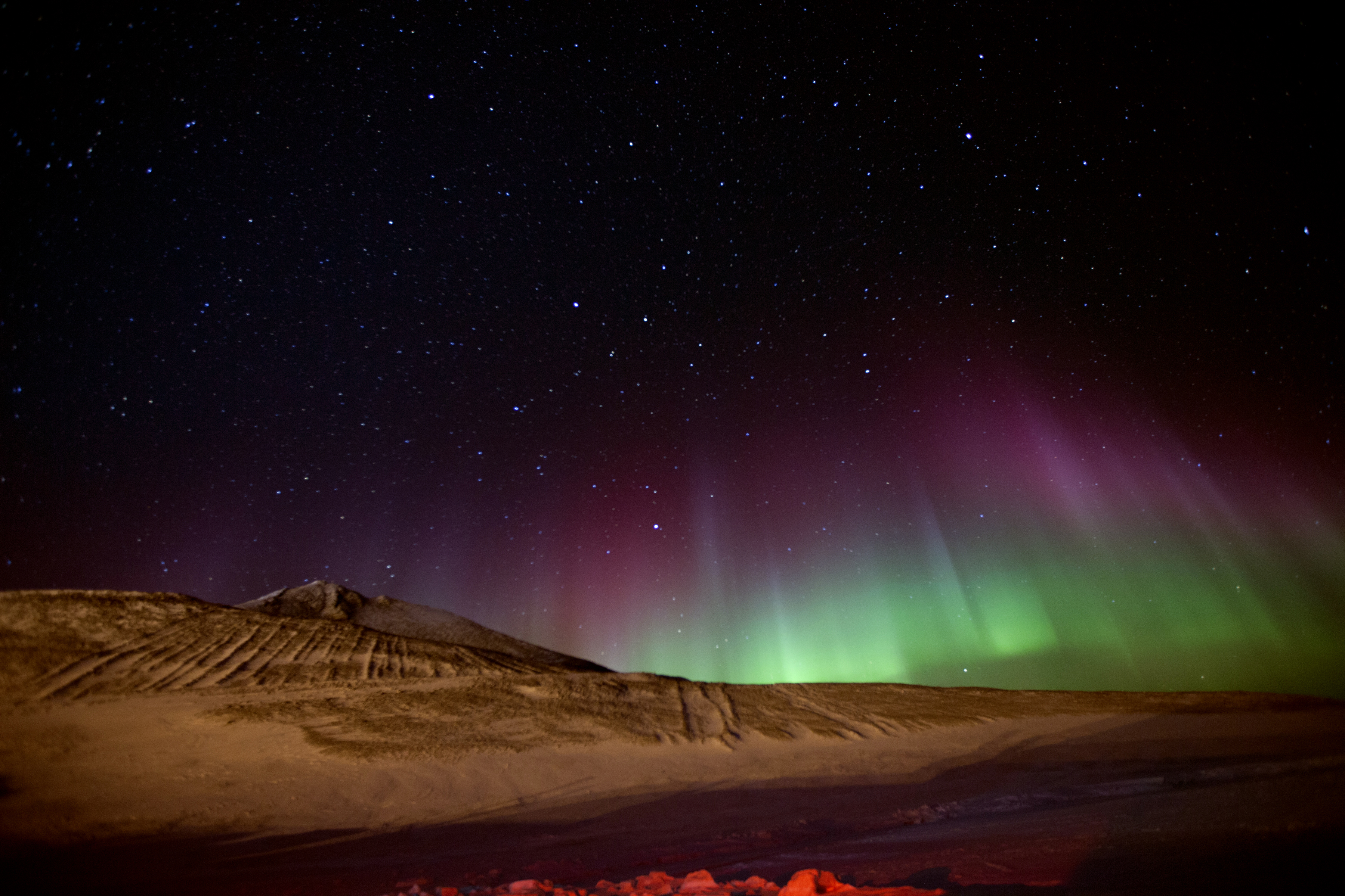Auroras and Milky Way illuminate the night sky over Ross Island.