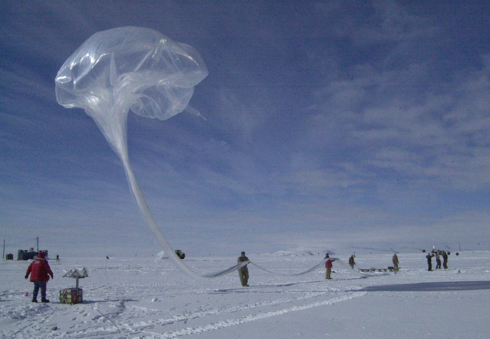 People hold a large balloon on snow.