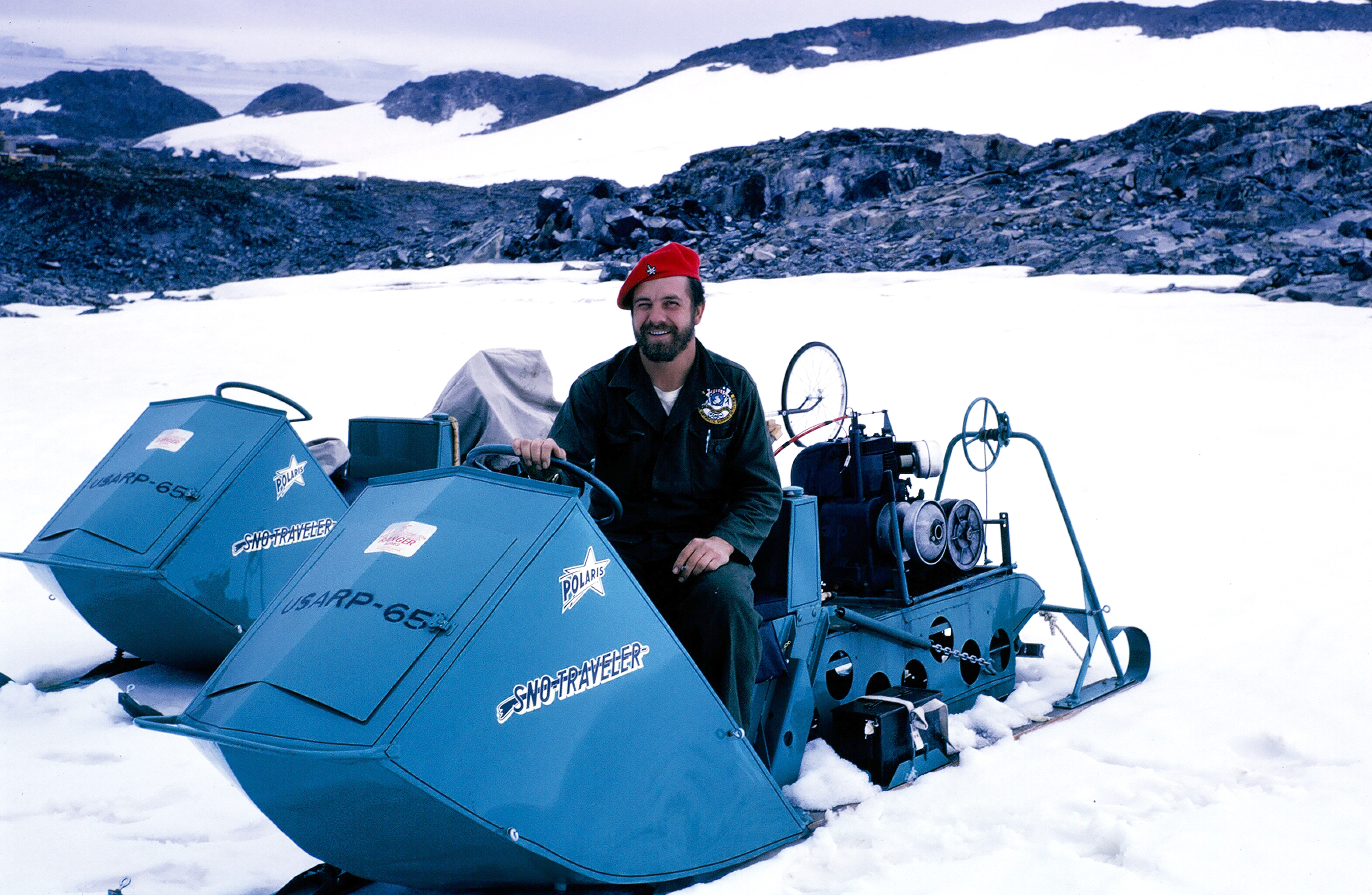 Man in beret sits on a snowmobile.
