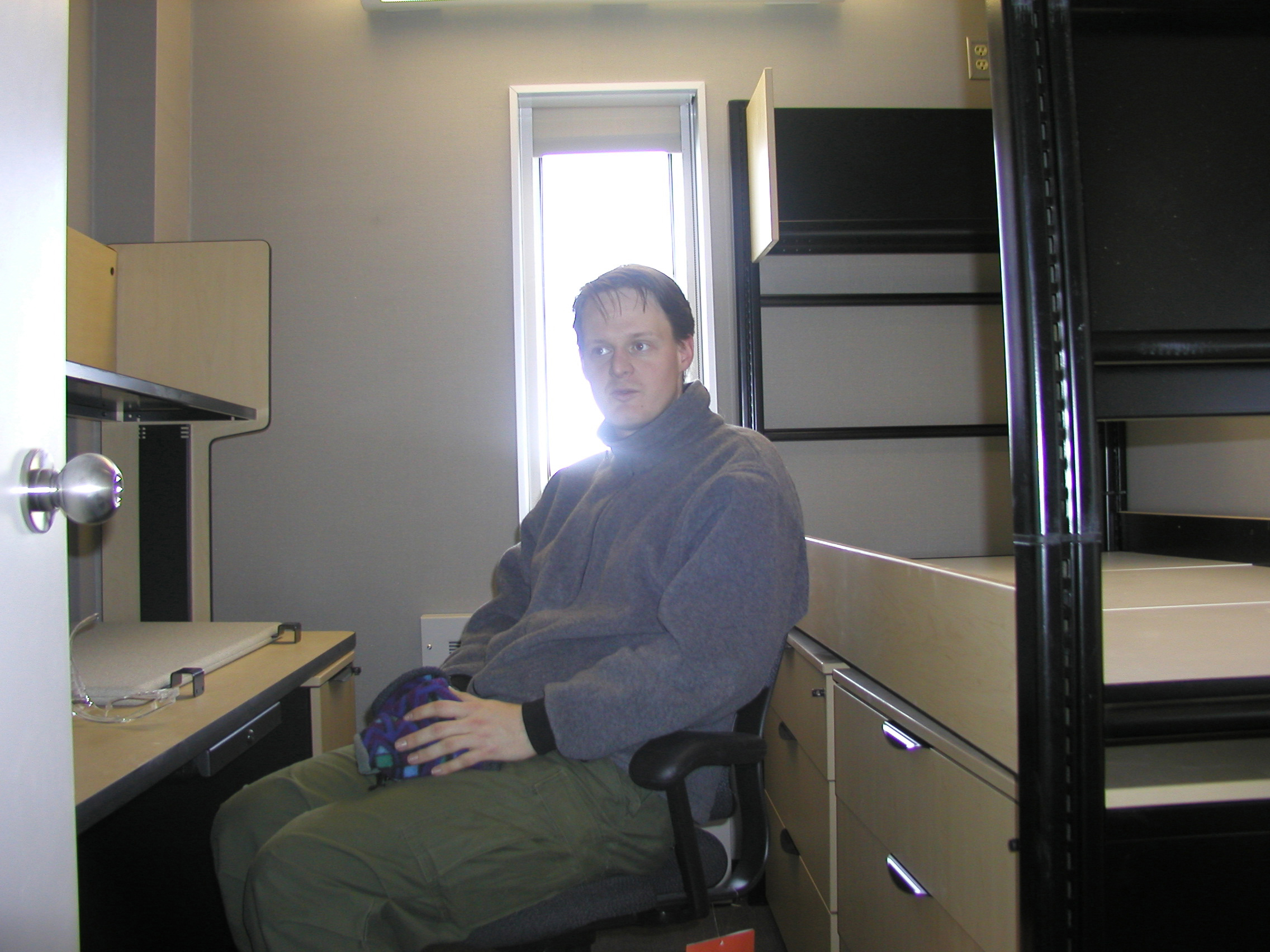 A man sits in a dorm room.