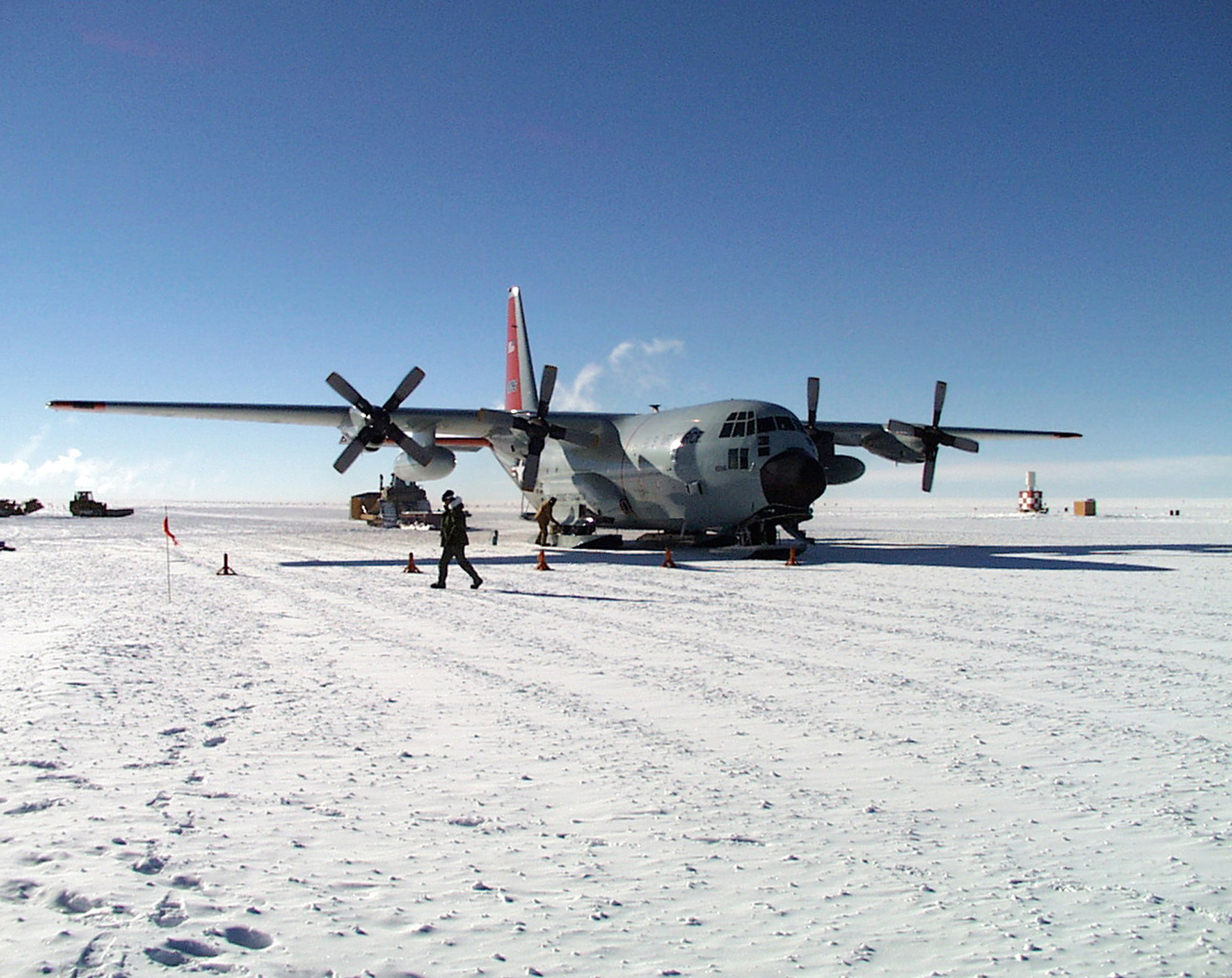 A ski-equipped propellered airplane sits on a snow-covered tarmac.