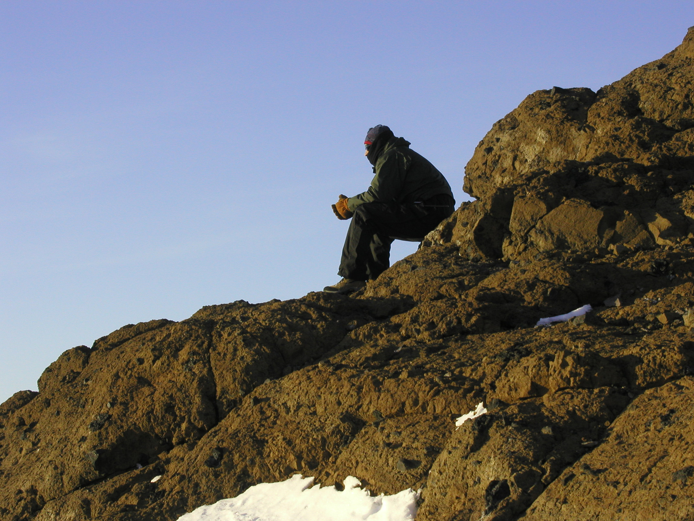 A person in profile sits on rocks.