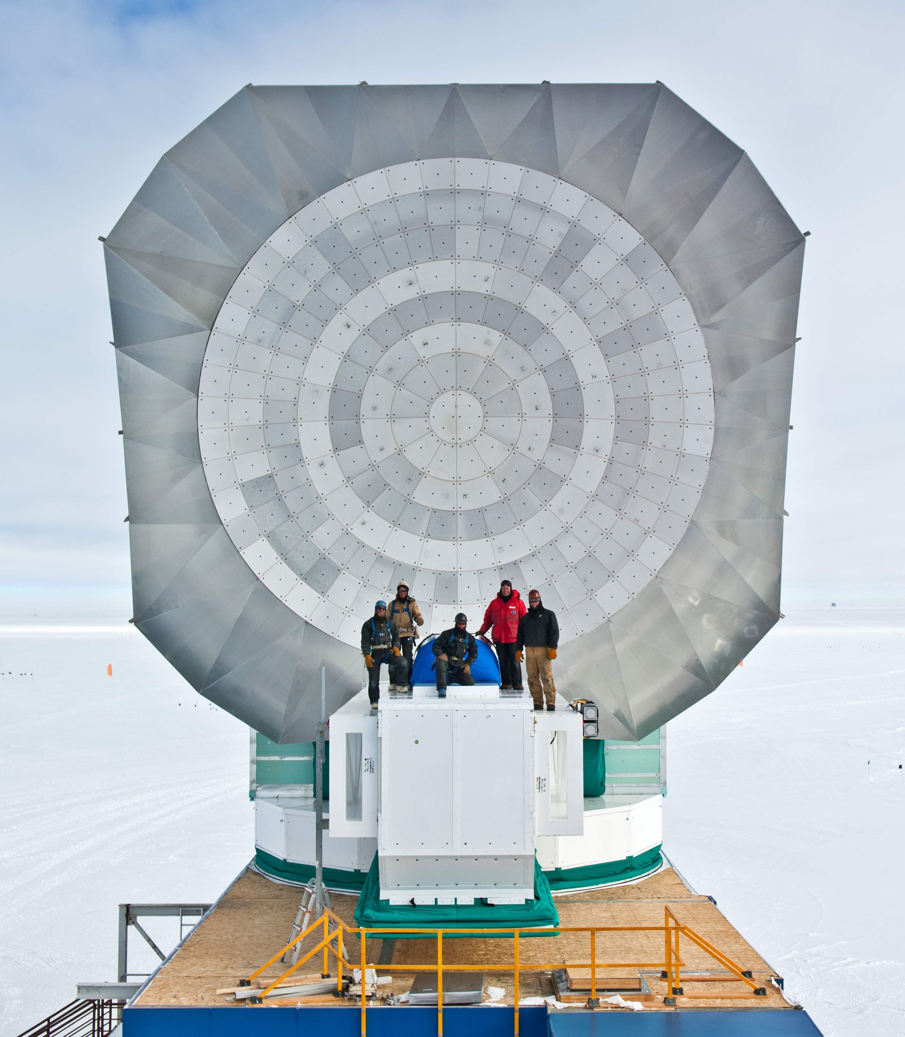 Five men in front of a parabolic dish.