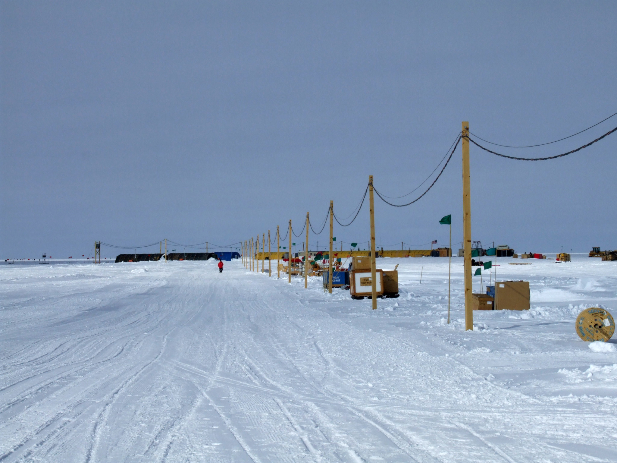 A line of electrical poles are erected in the snow.