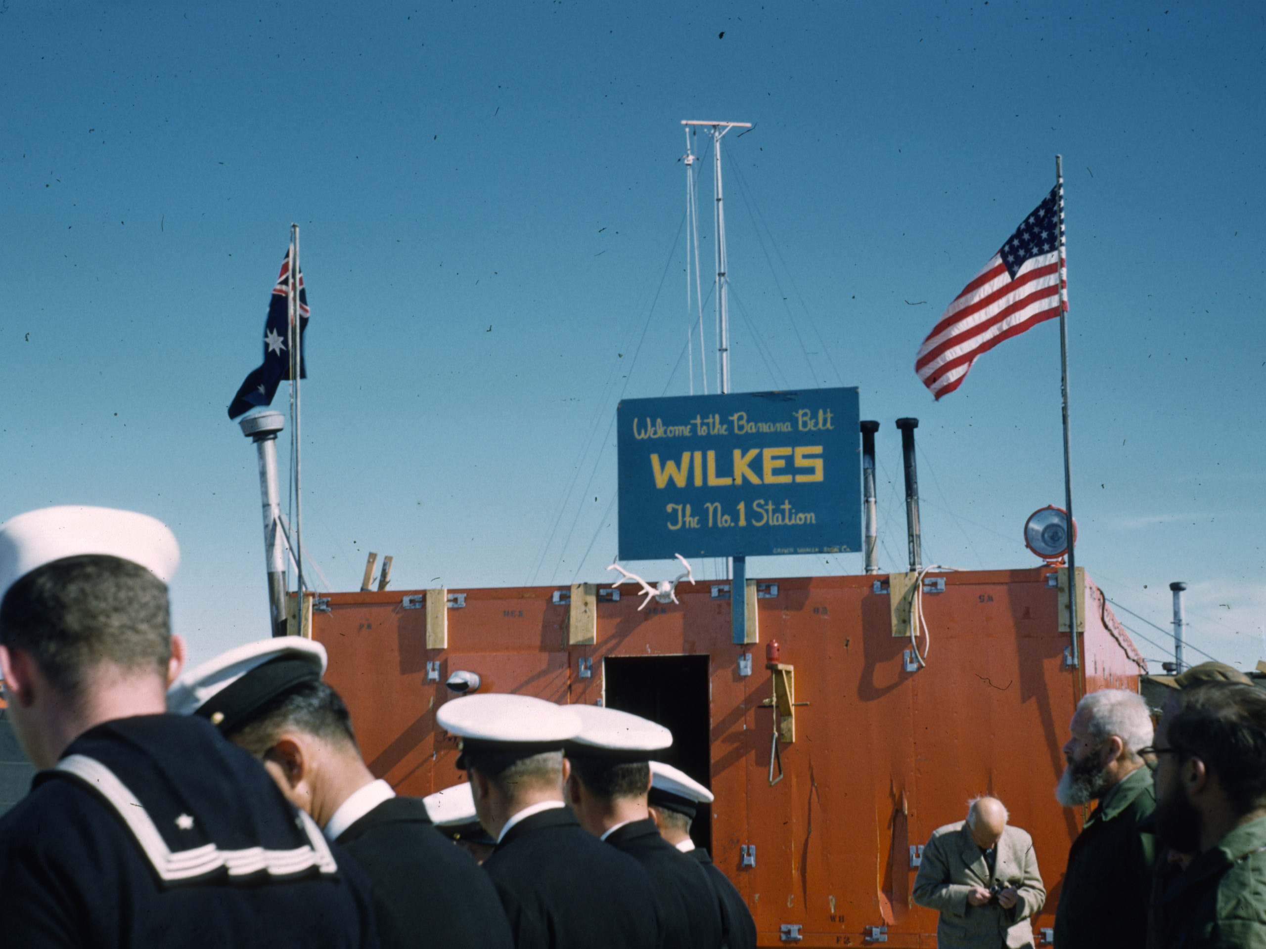 US Navy sailors stand in front of a building.