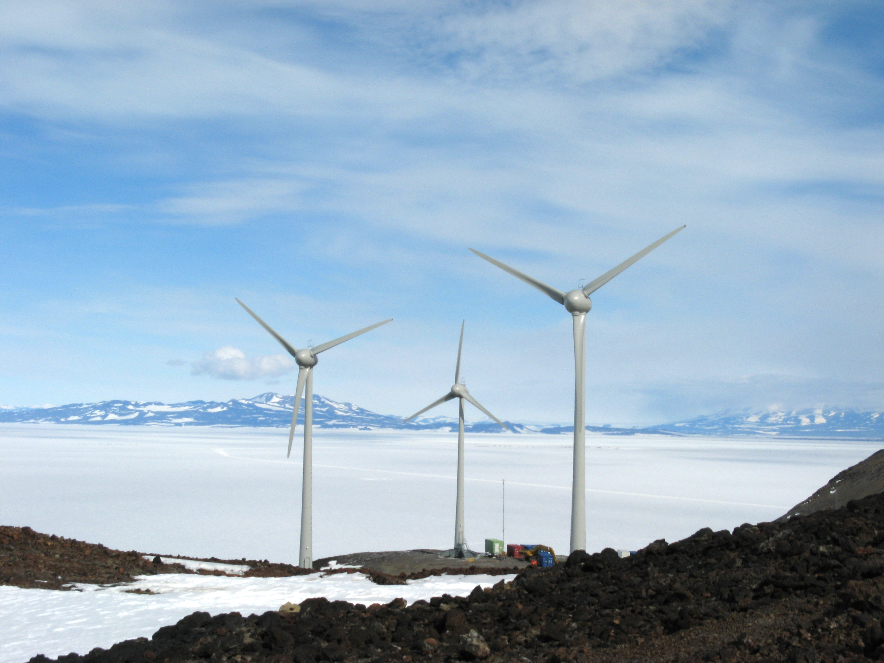 Wind turbines spin near icy place.