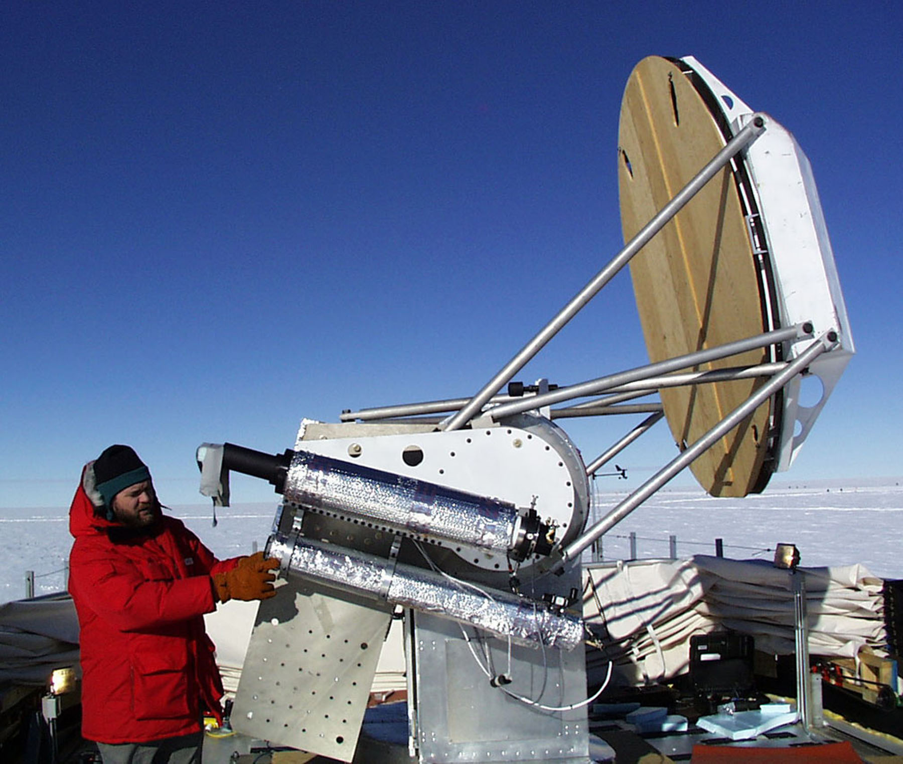 A man in a red parka works with a satellite receiver.
