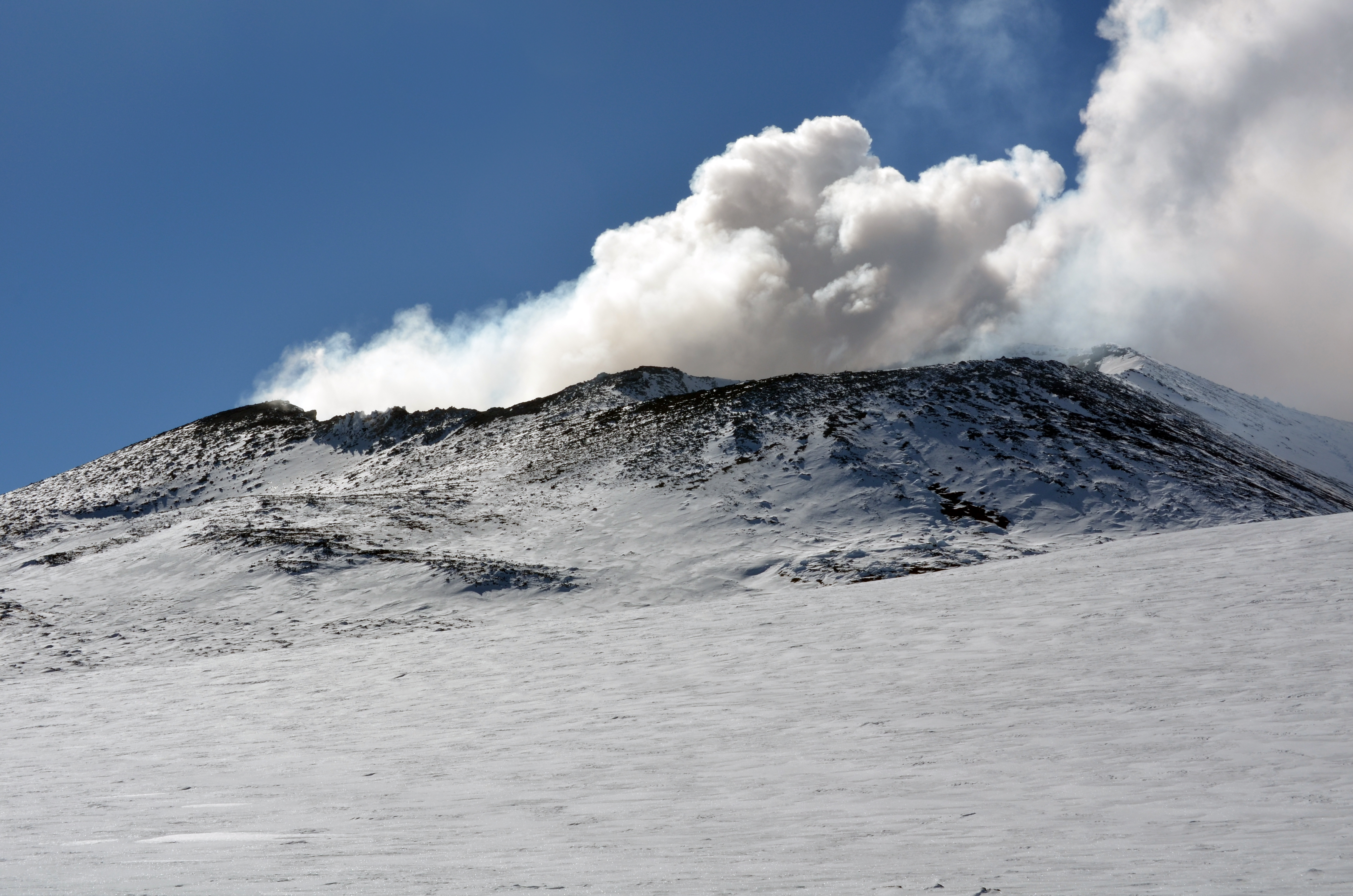 Smoke rises from a volcanic crater.
