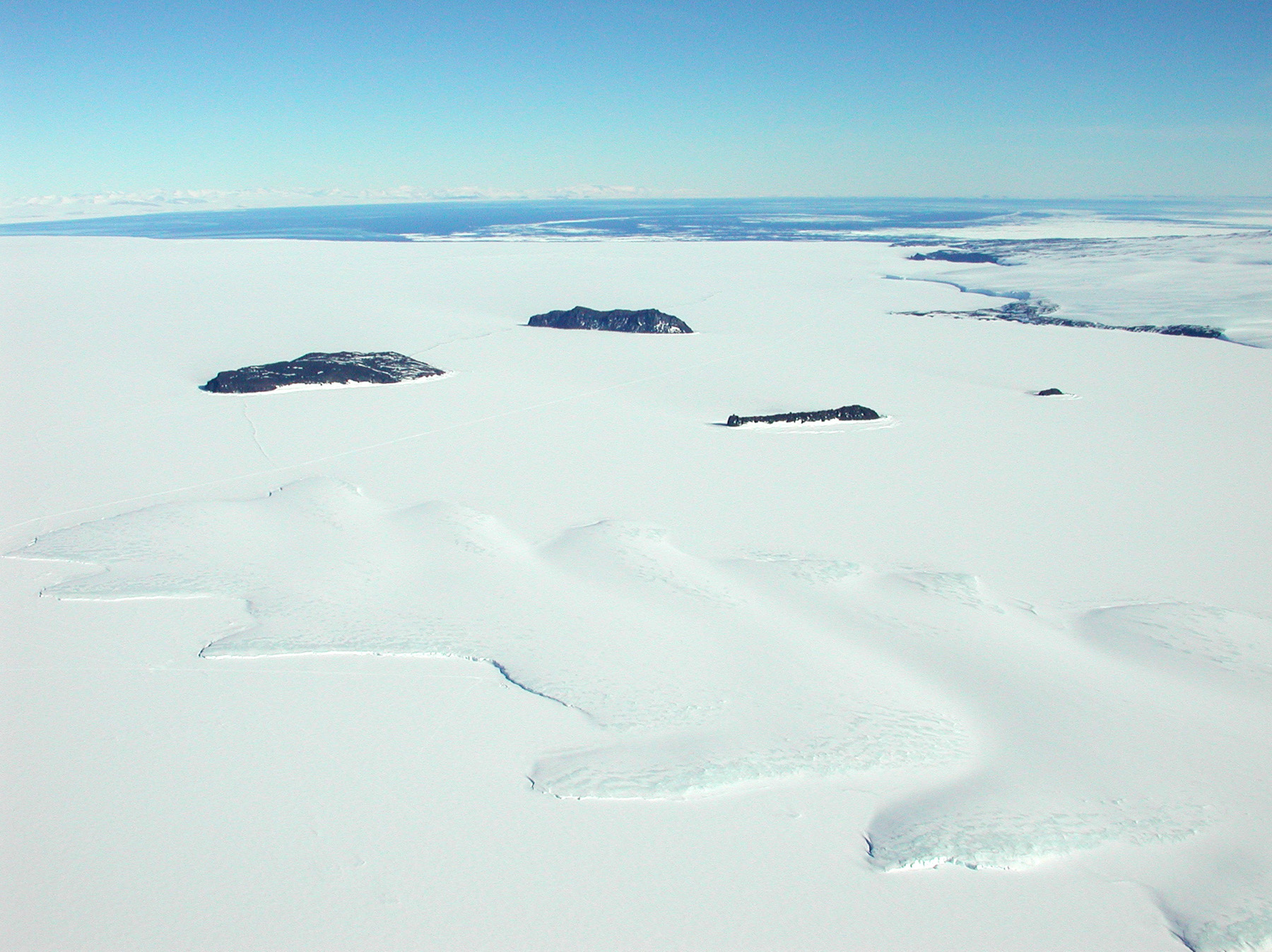 Aerial view of ice covered ocean, with small islands portruding through the ice.