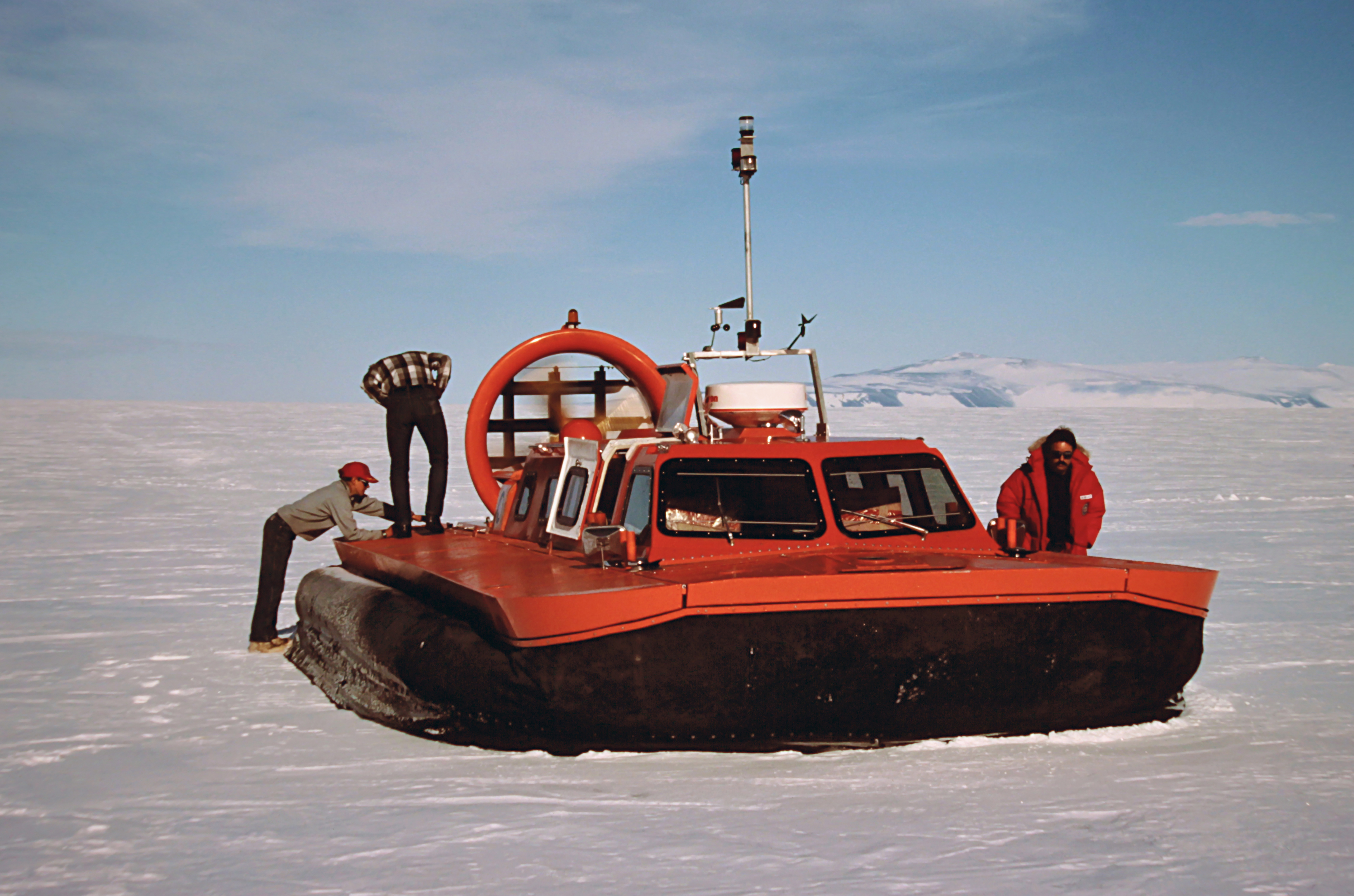 A red hovercraft parked on snowy terrain.
