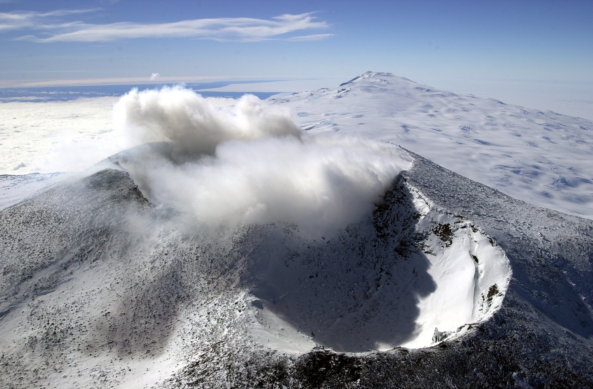 Aerial view of a volcanic cone with steam coming from it.