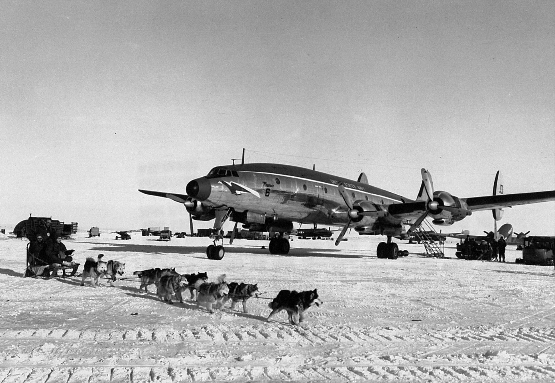 Airplane and dogsled team on snow.