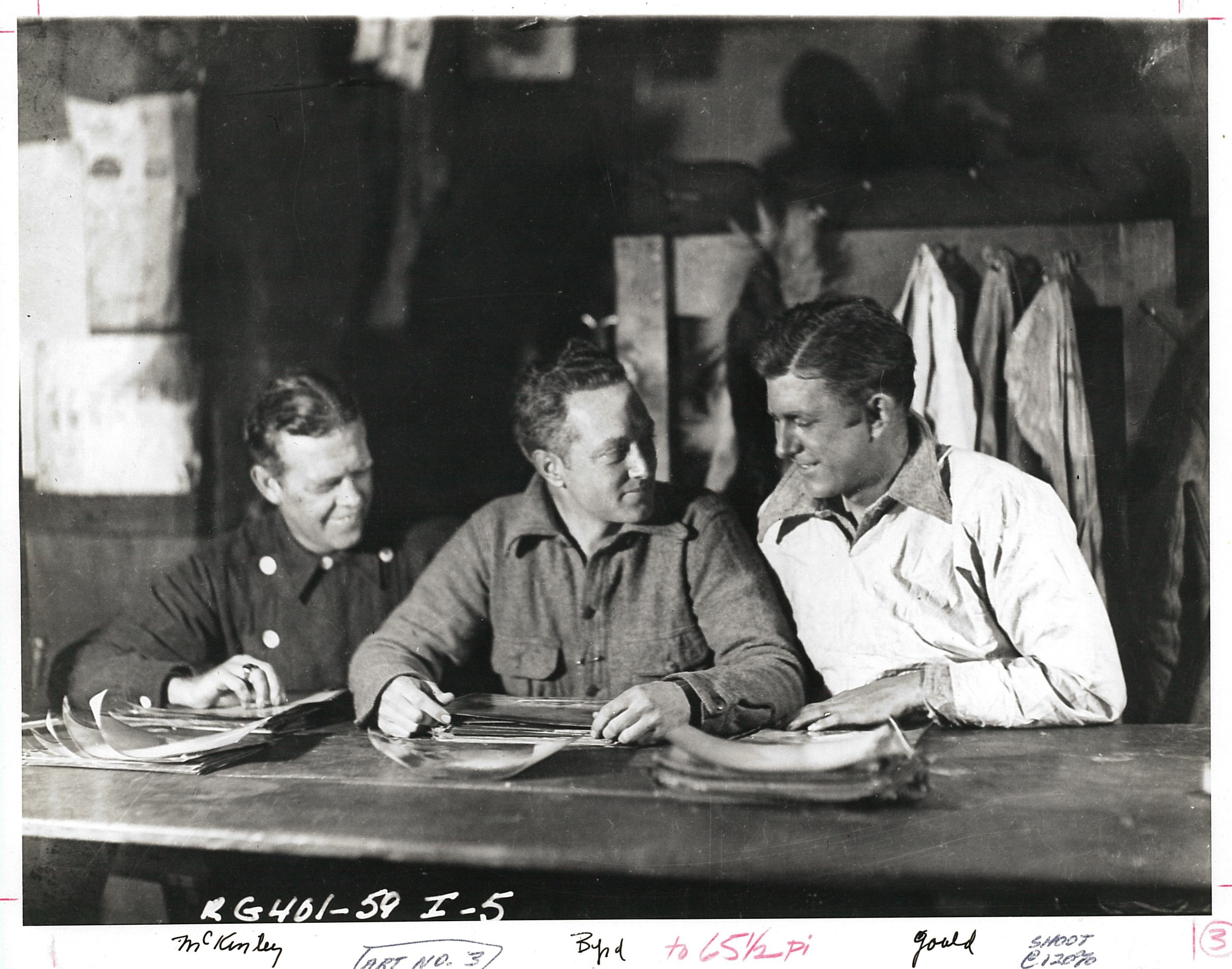 Three men at a table looking at papers.