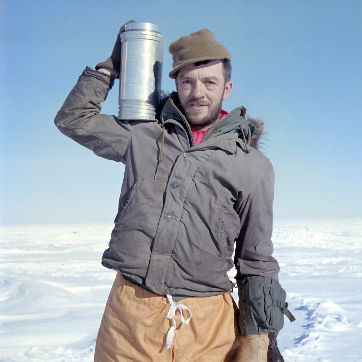 A man holding a metal cylinder standing outside.