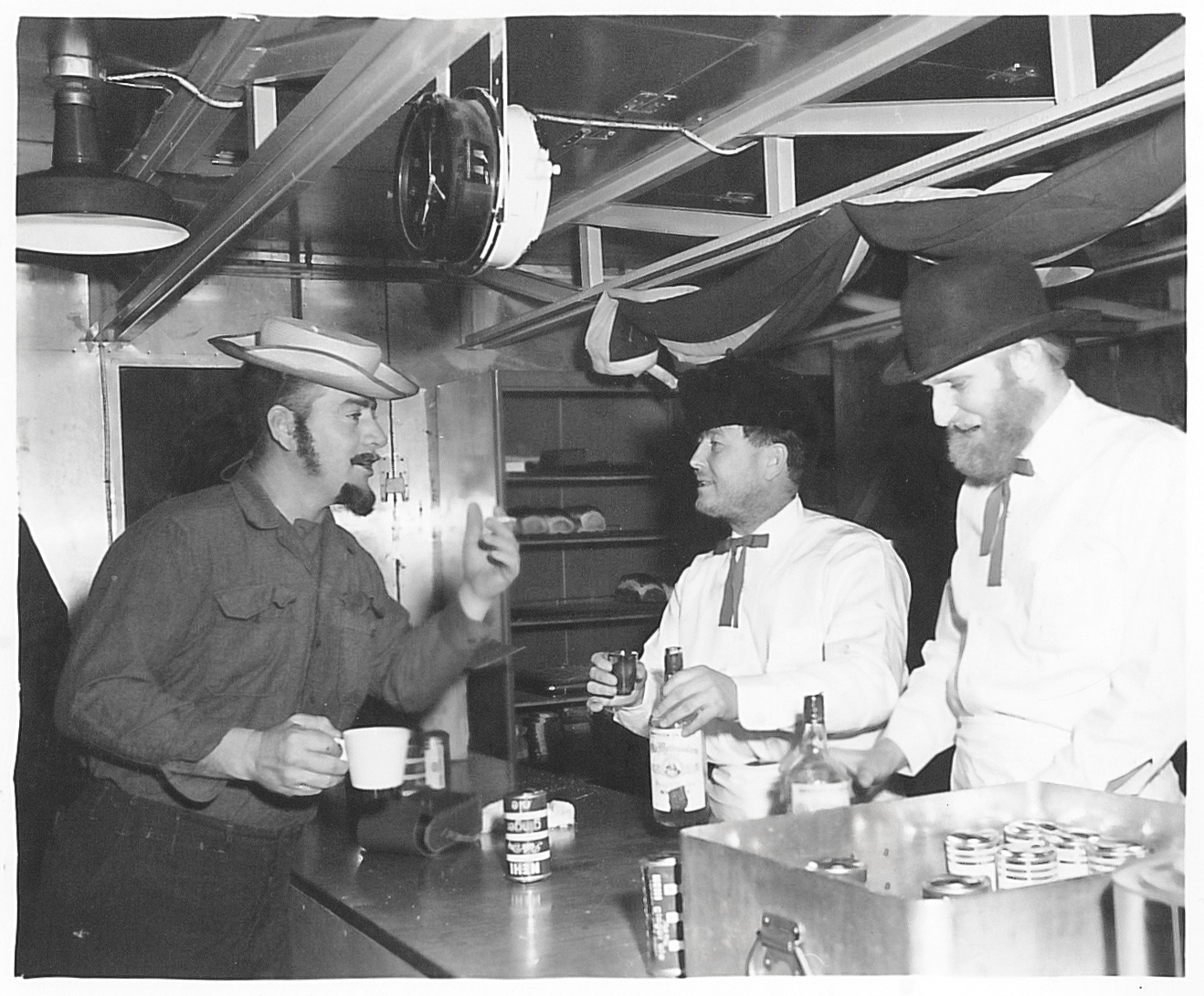 Three men indoors talking at a table.