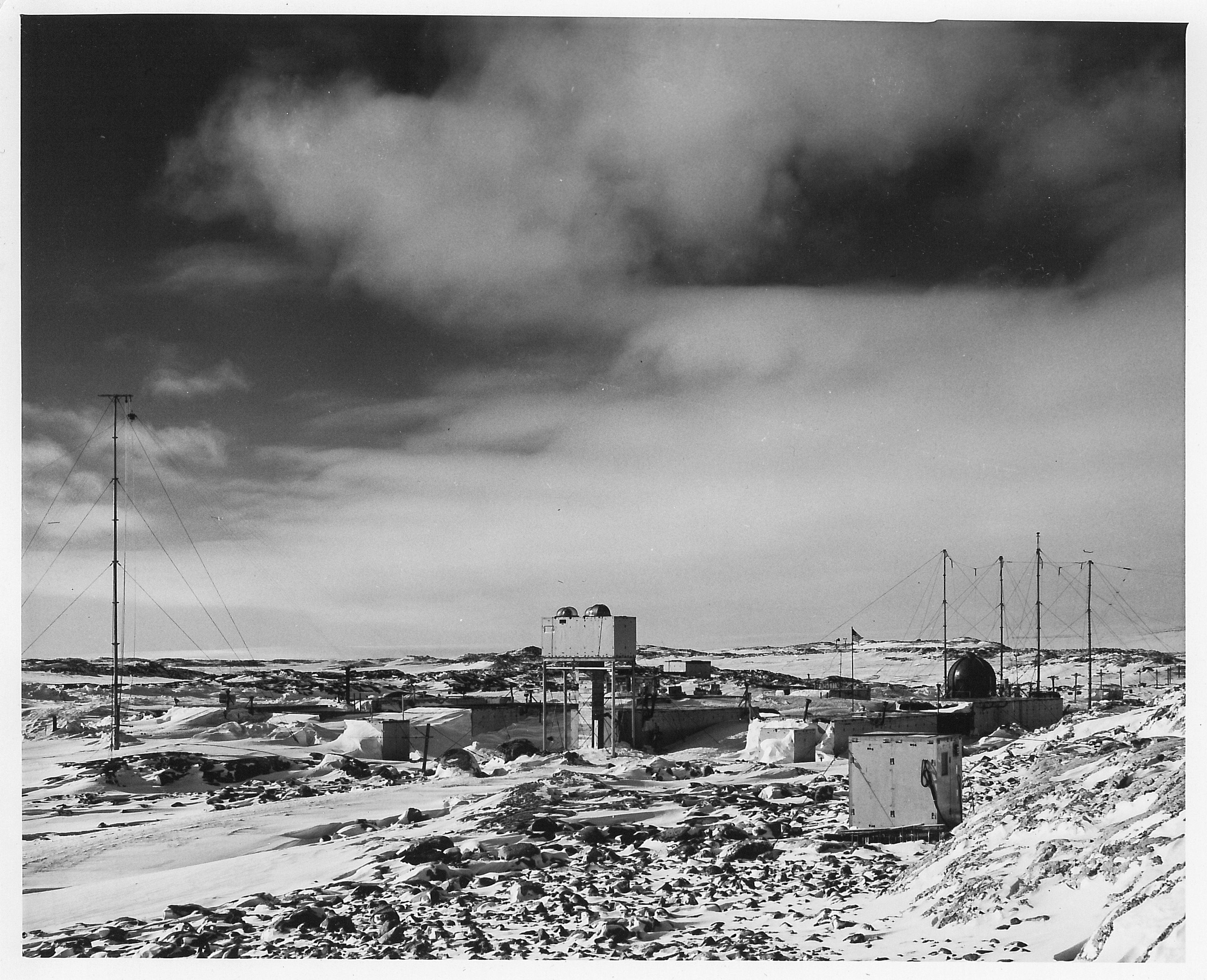 A series of small buildings on frozen rocky terrain.