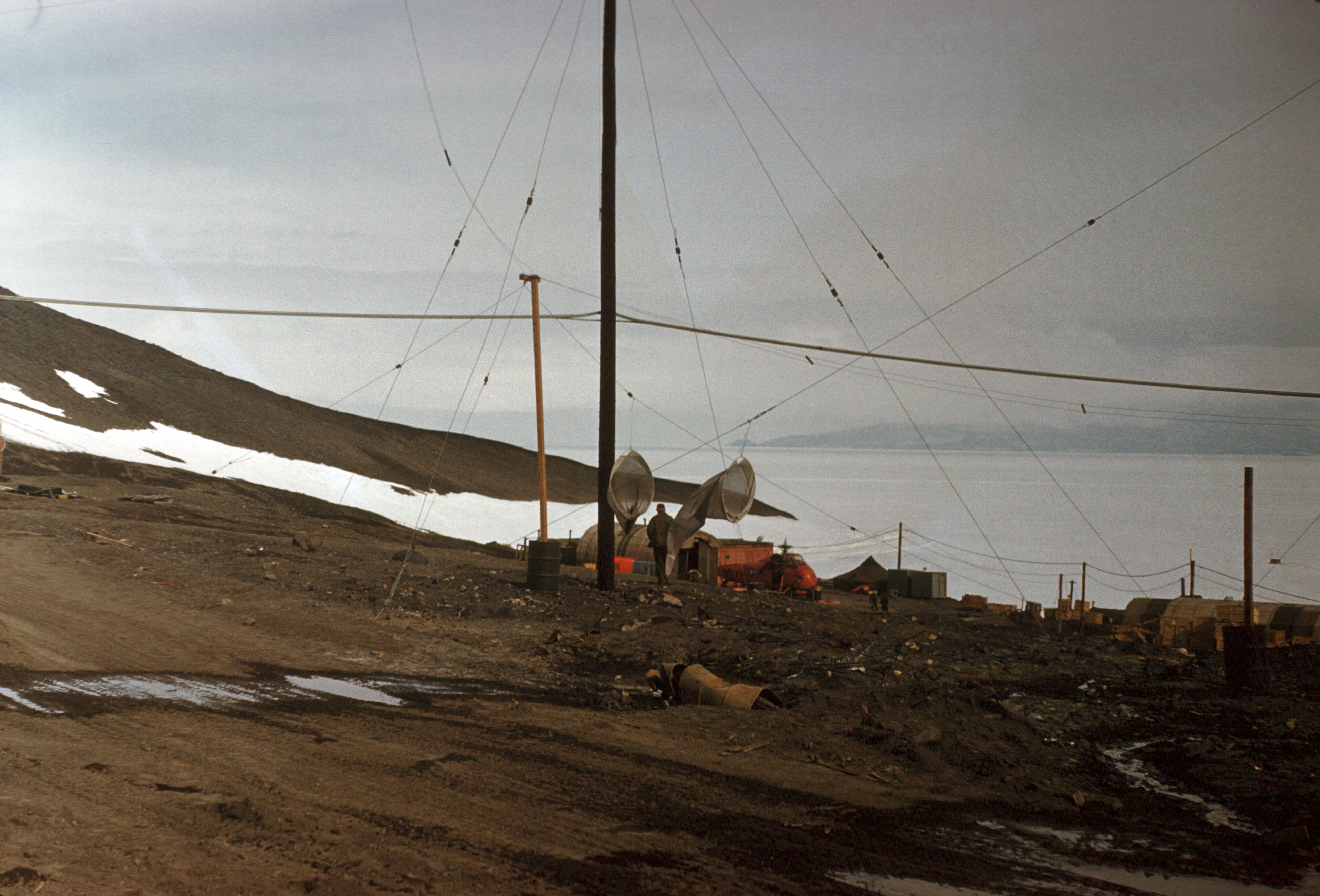 A rocky hillside with buildings and a helicopter.