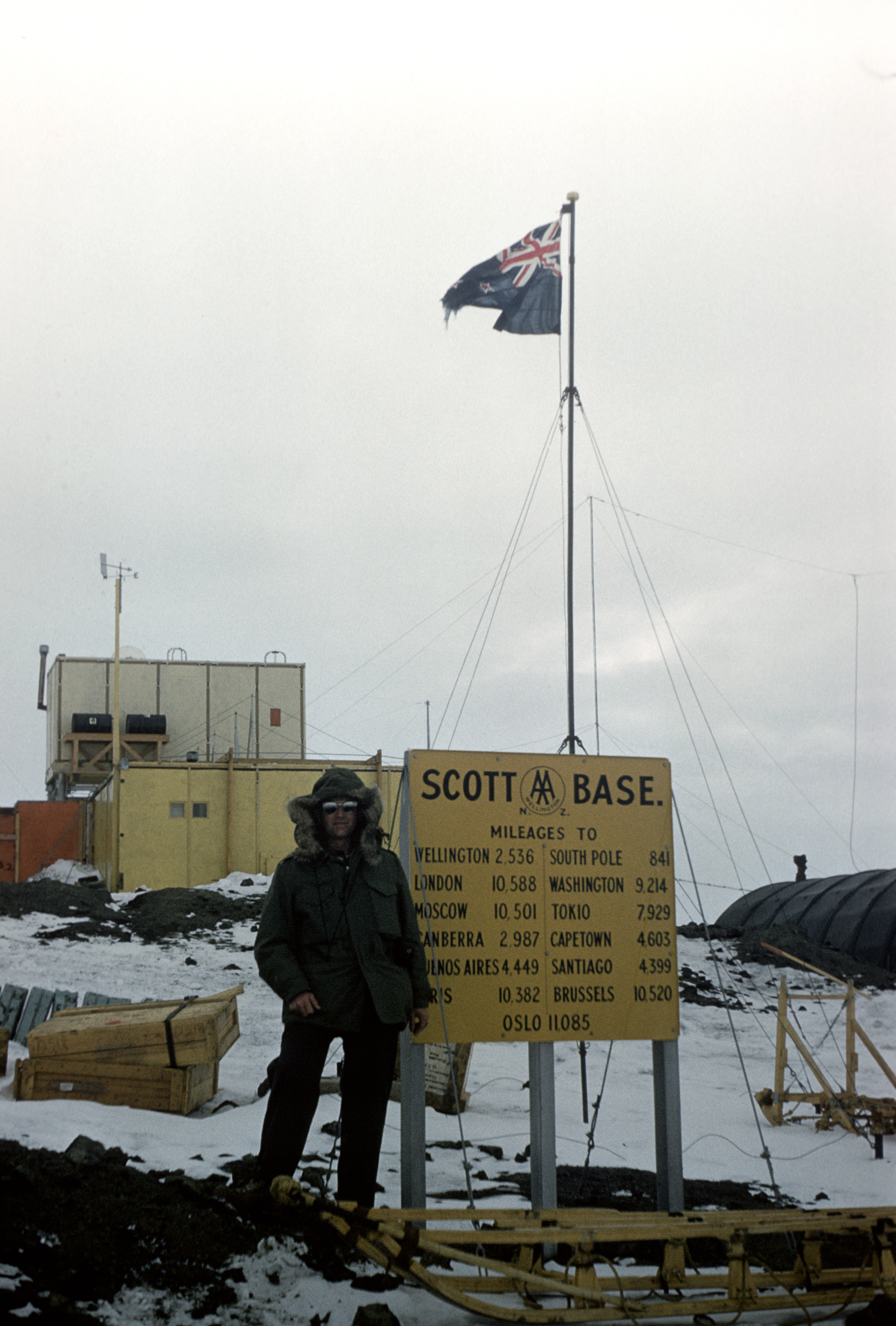 A man standing next to a sign that says Scott Base.