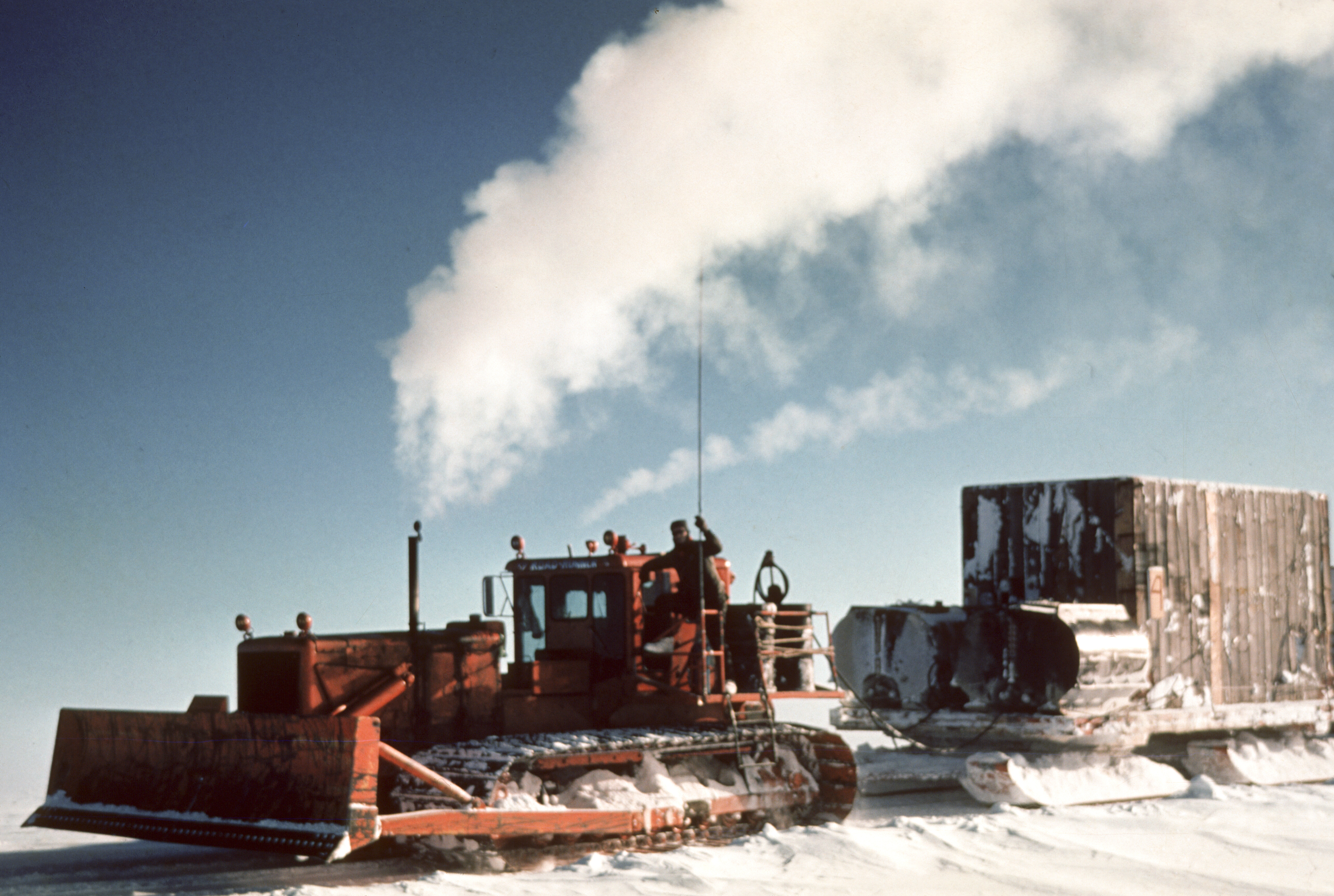 A Caterpillar tractor pulling a large sled across snow.