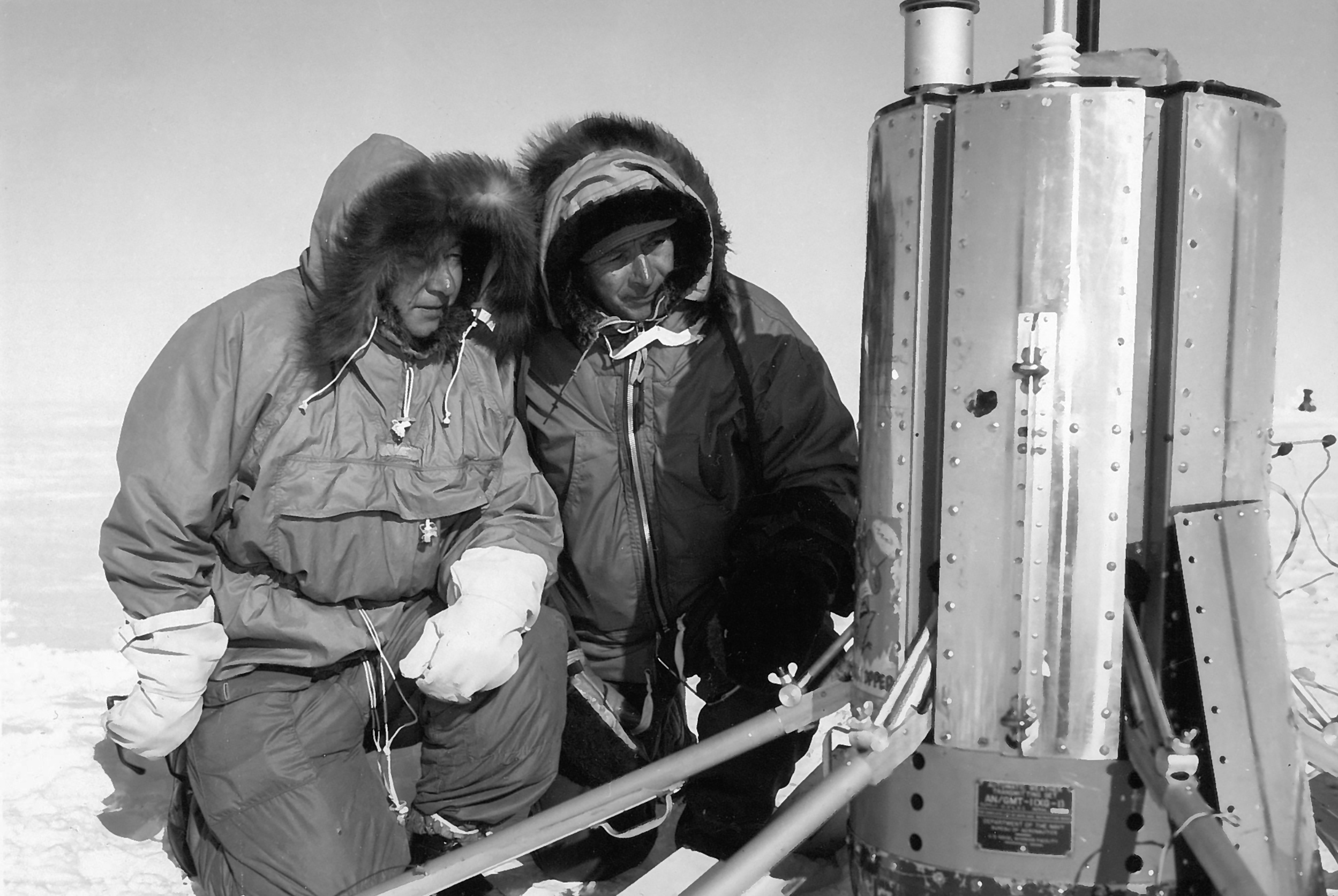 1960 photo of two people operating science equipment.
