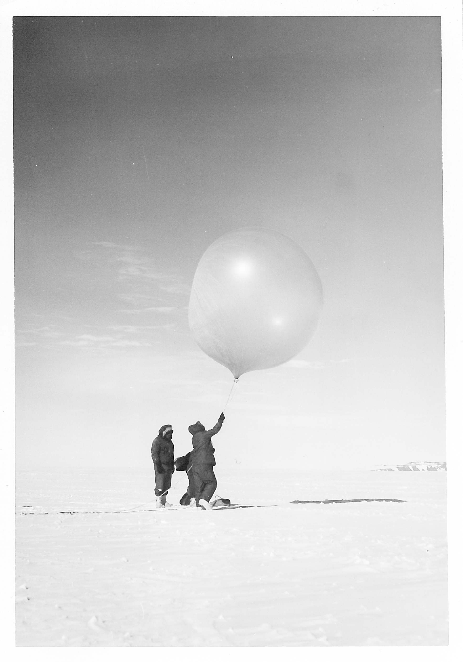 Two people holding a large helium balloon.