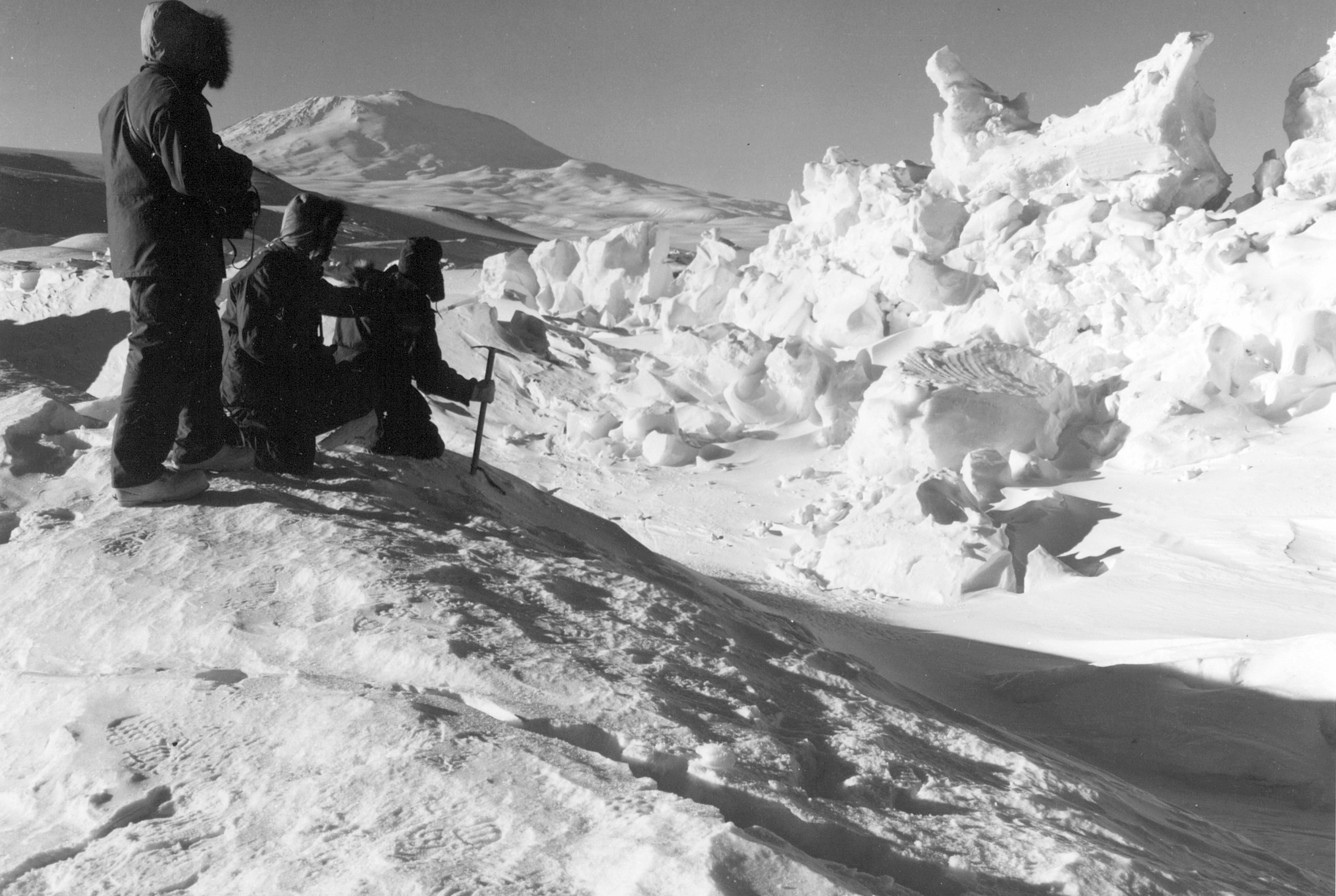 Men near an uplifted pressure ridge of snow and ice.