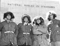 Four men dressed in winter parkas pose in front of the National Bureau of Standards in Washington, D.C.