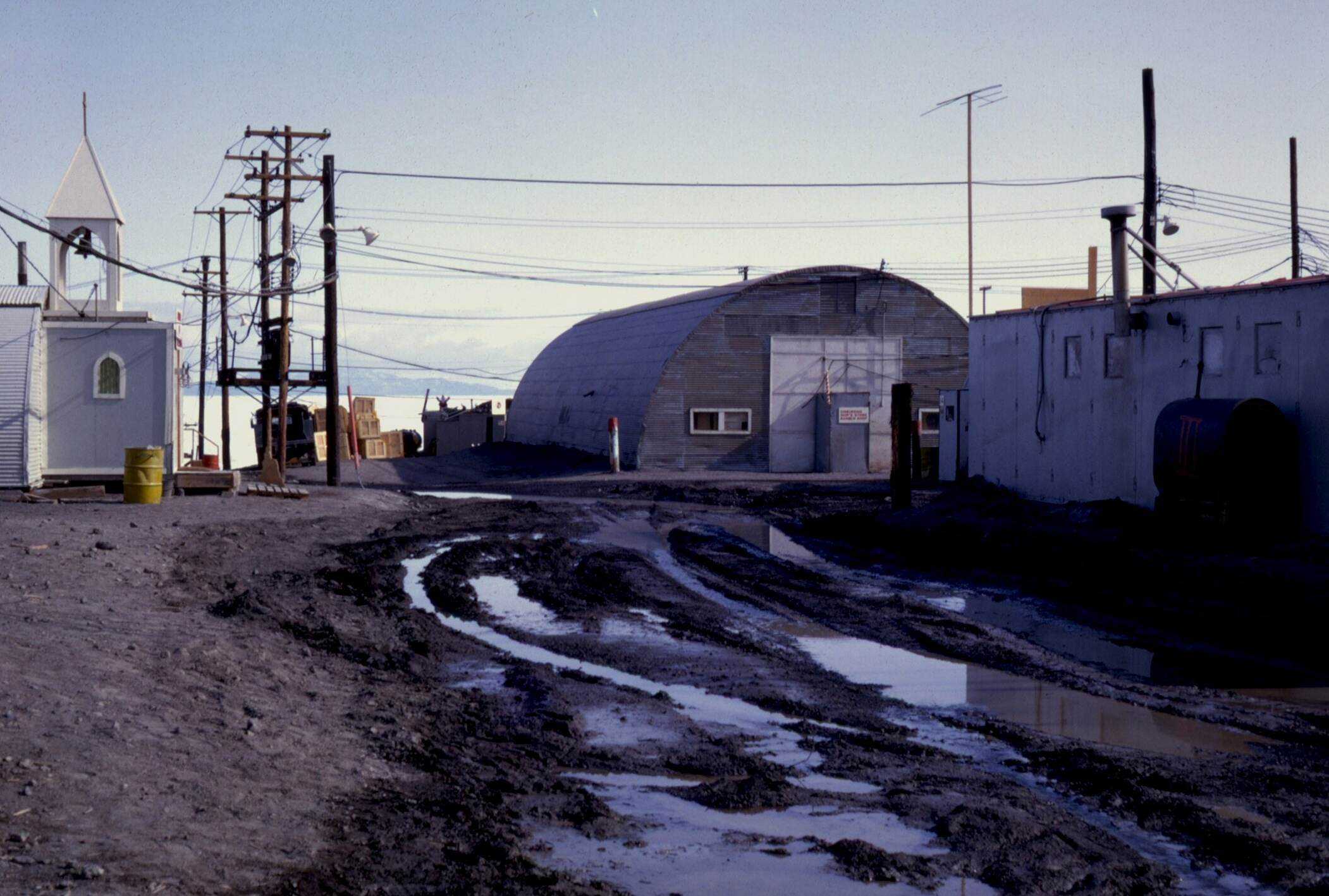 A muddy street between buildings.