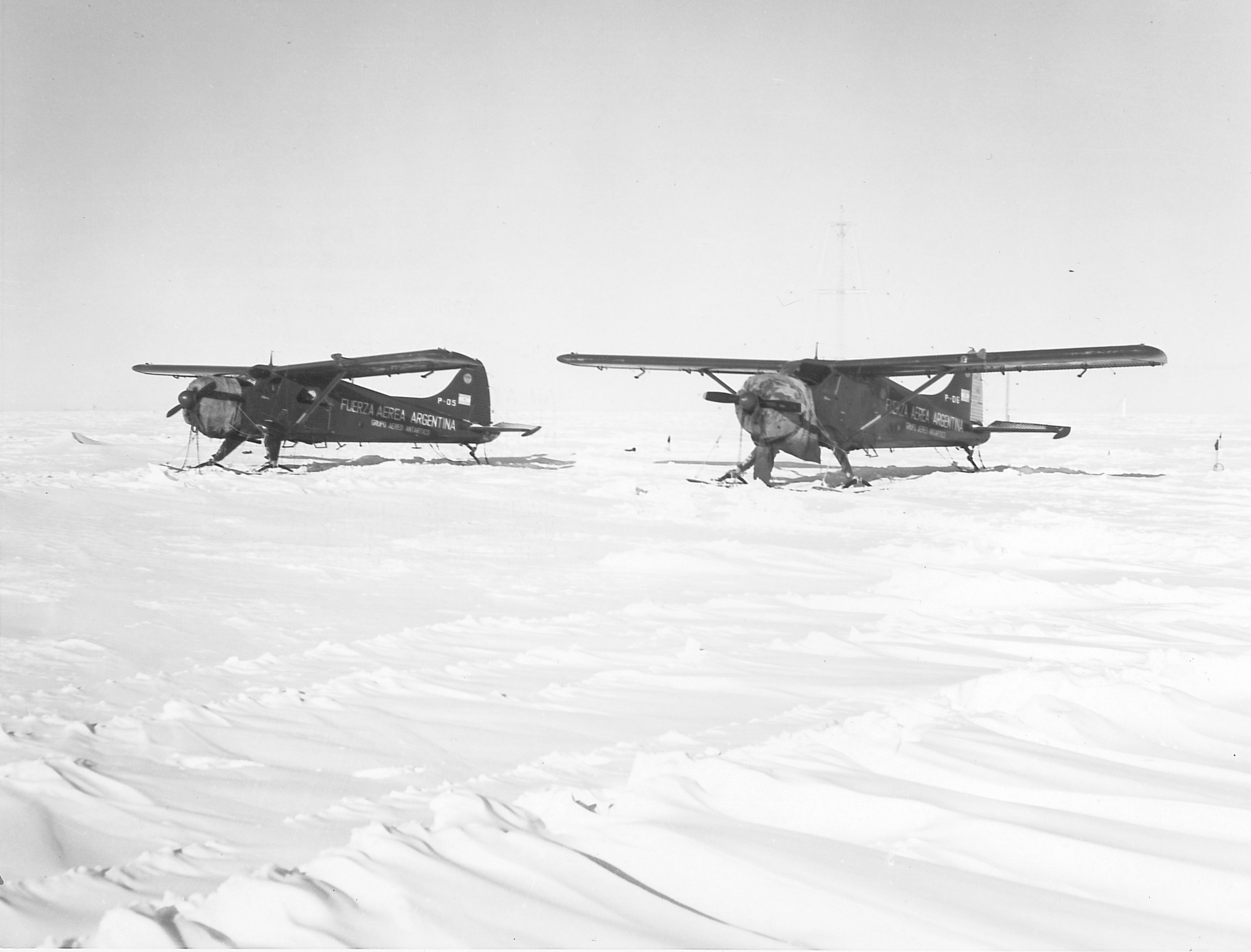 Two airplanes on a snowy landscape.