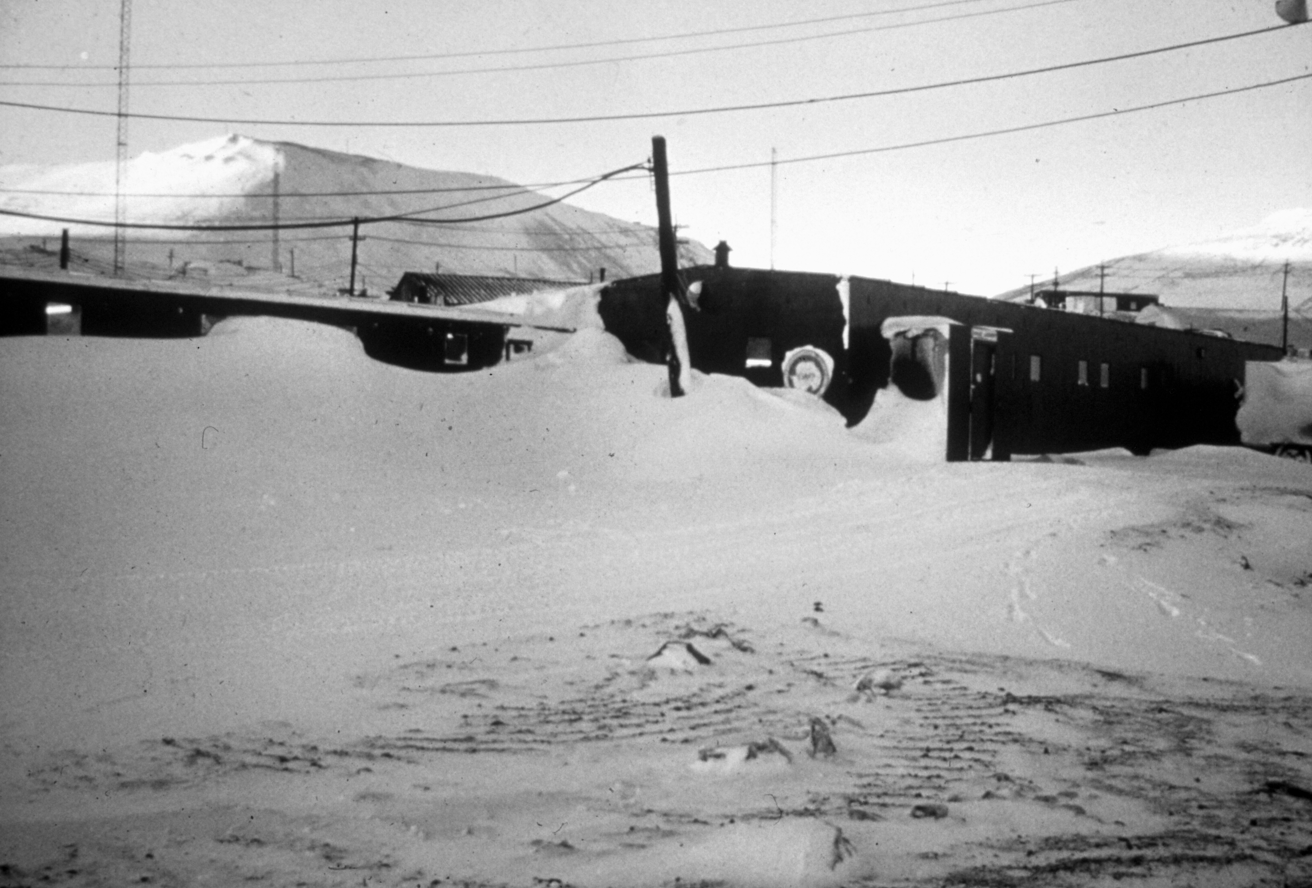 A black and white photo of snow covered buildings.