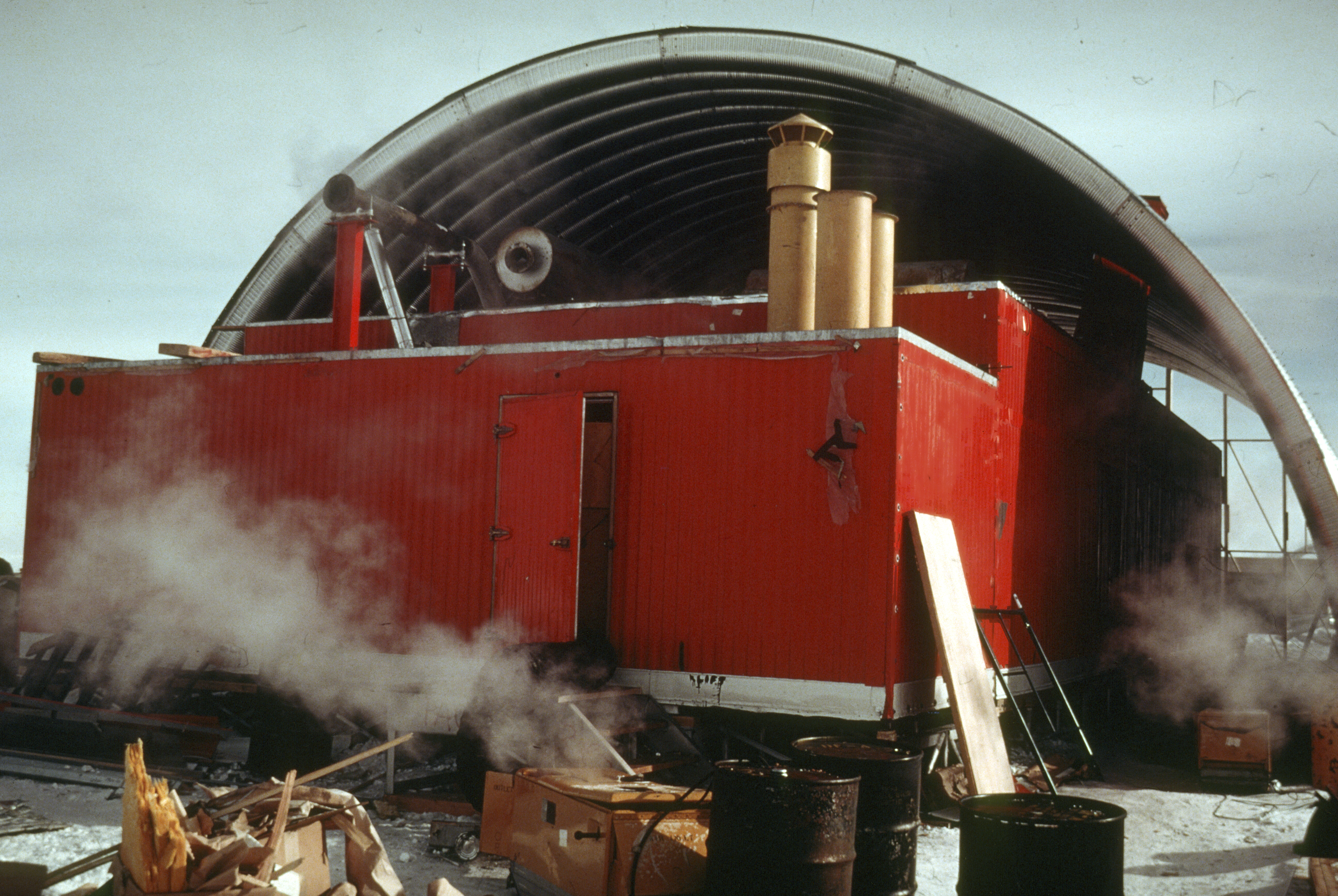 A red building under a steel arch.