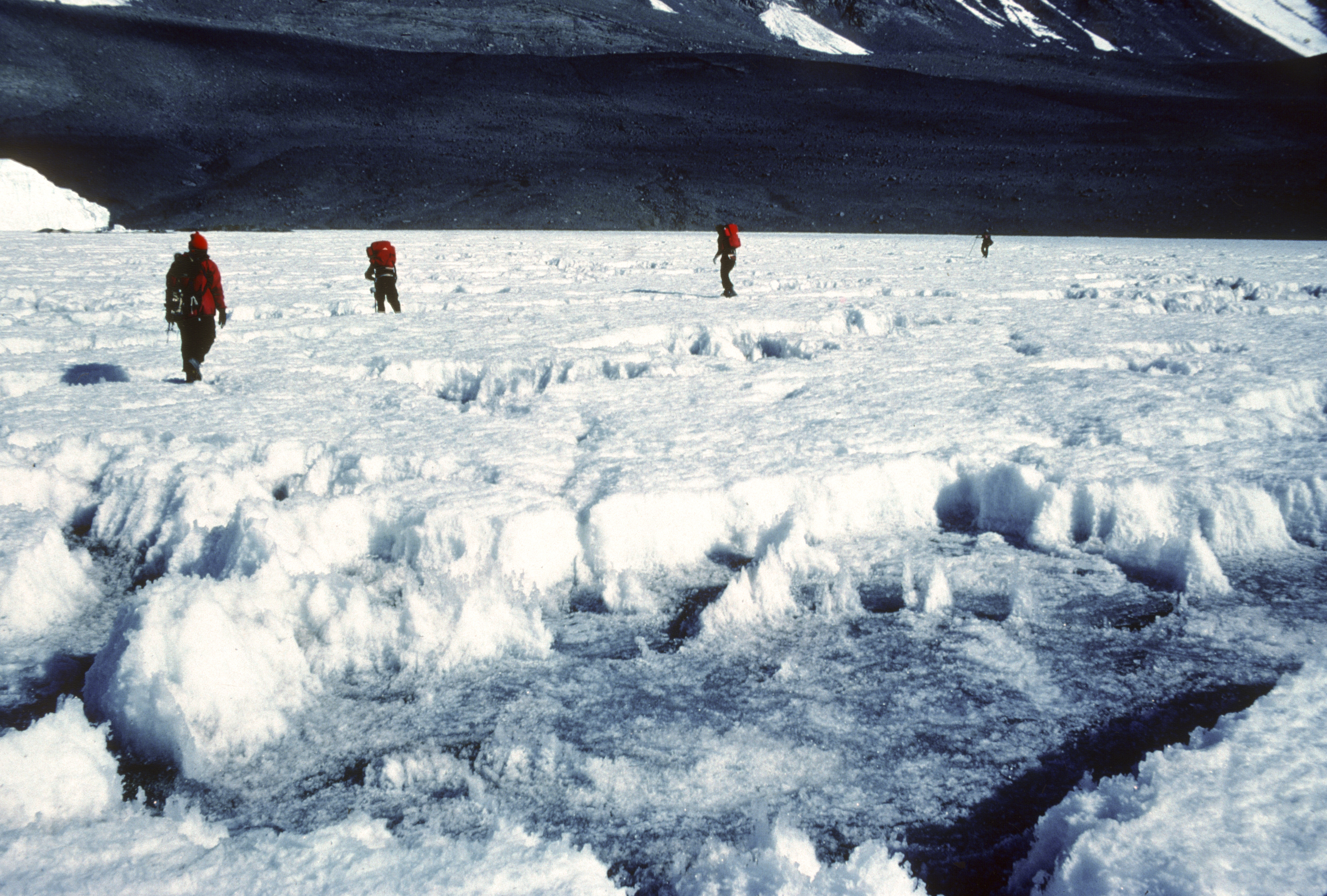 Four people walking across a jagged ice field.